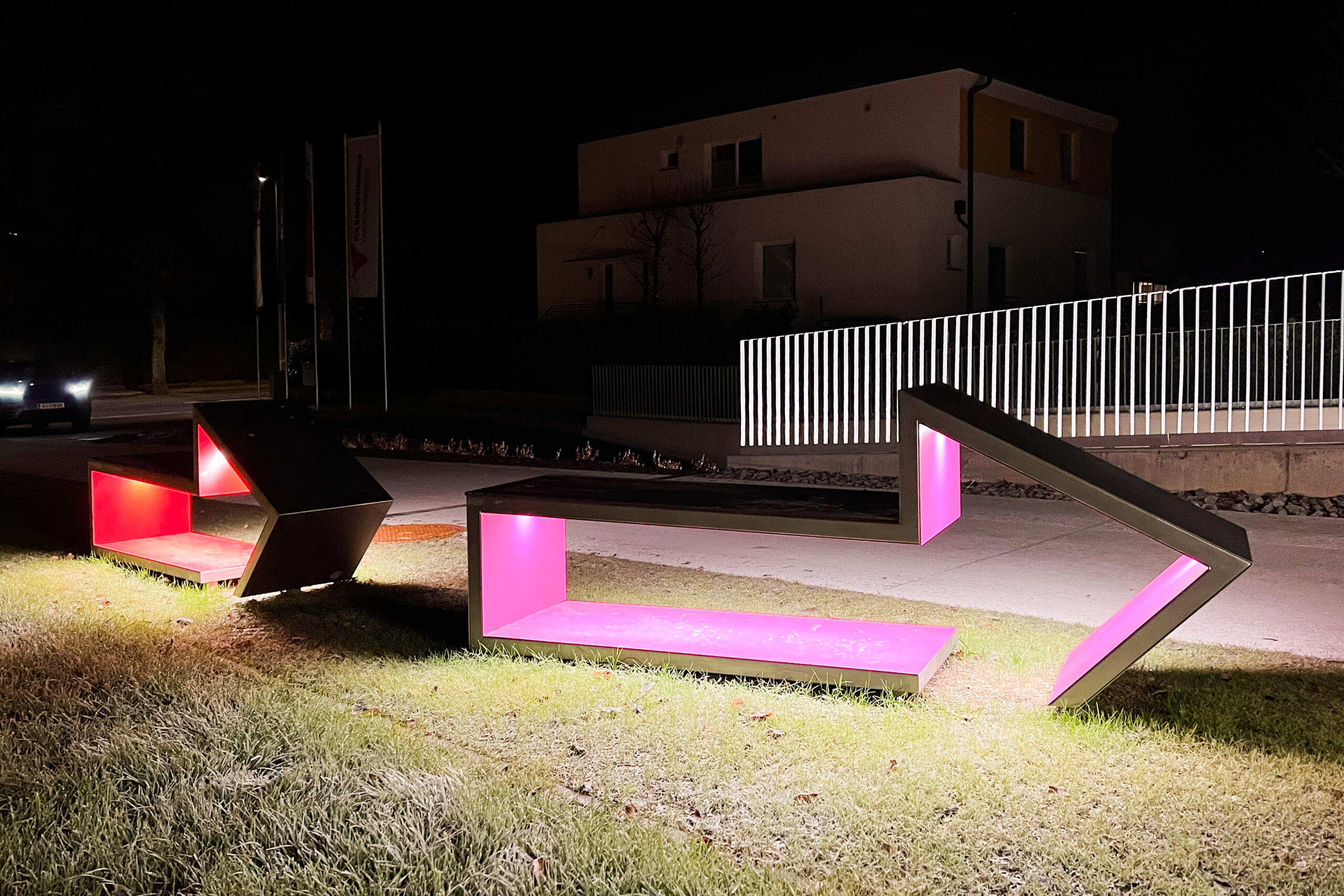 Moderne Sitzbänke mit pinker LED-Beleuchtung im Außenbereich, illuminiert von Illumina.