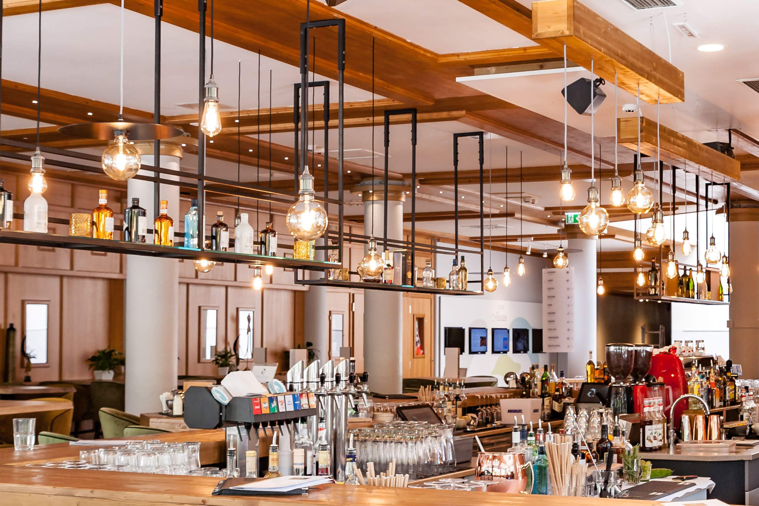 Moderne Bar mit Hängeleuchten und einer Auswahl an Flaschen – Lichtplanung von Illumina.