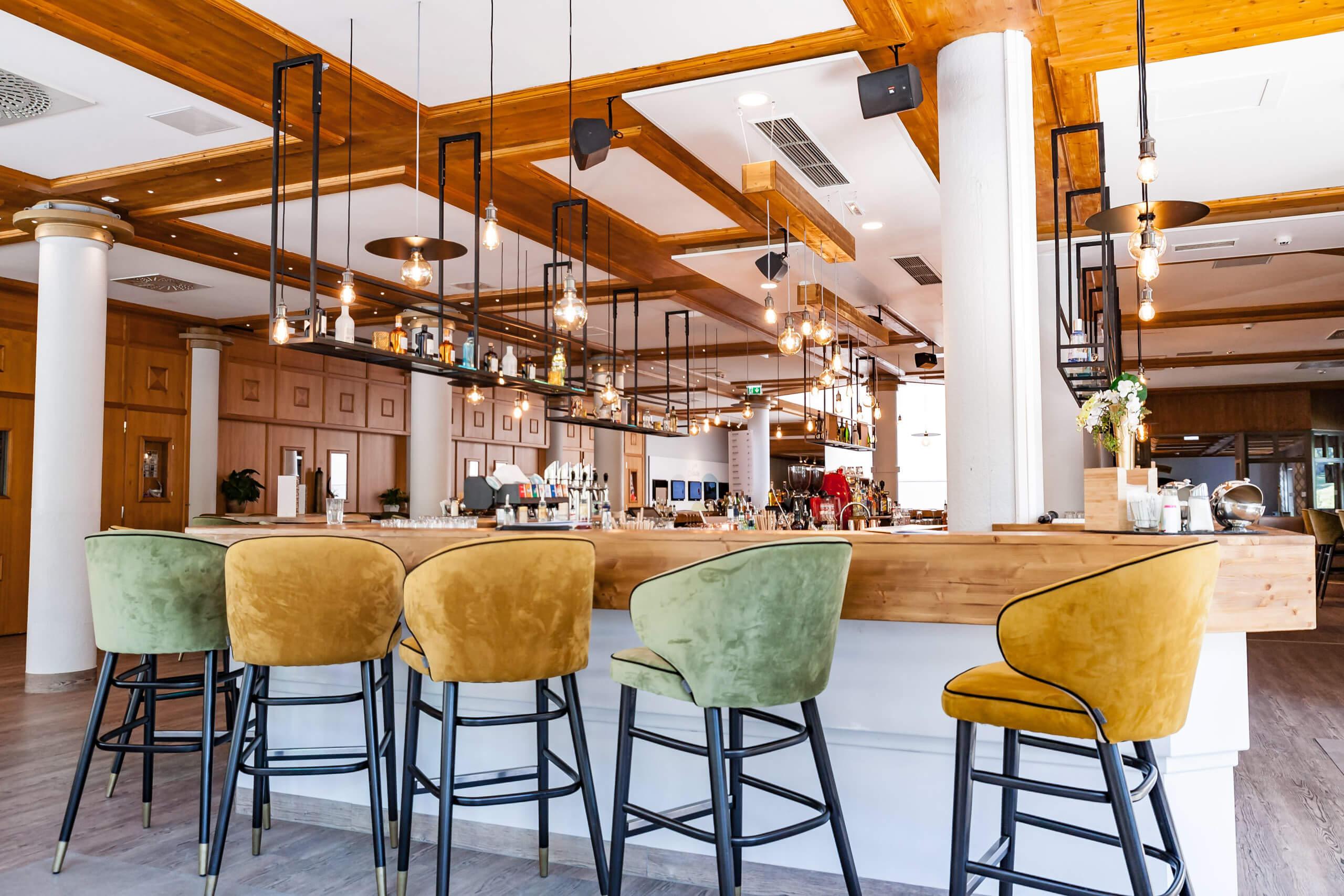 Moderne Bar mit stilvollen Hängeleuchten und bequemen Sitzmöbeln – Lichtplanung von Illumina.
