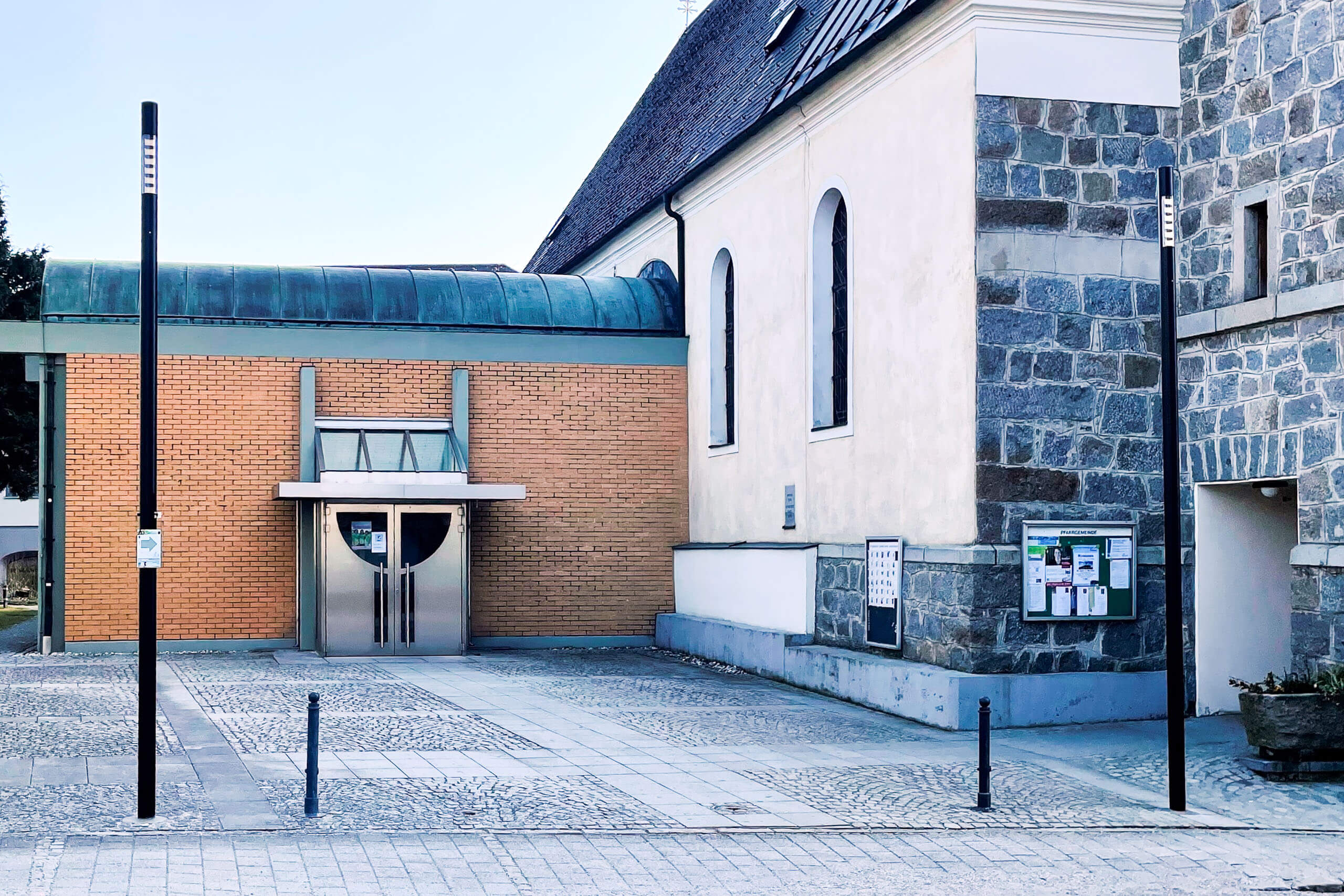Moderne Kirche mit Klinker-Anbau und stilvoller Außenbeleuchtung