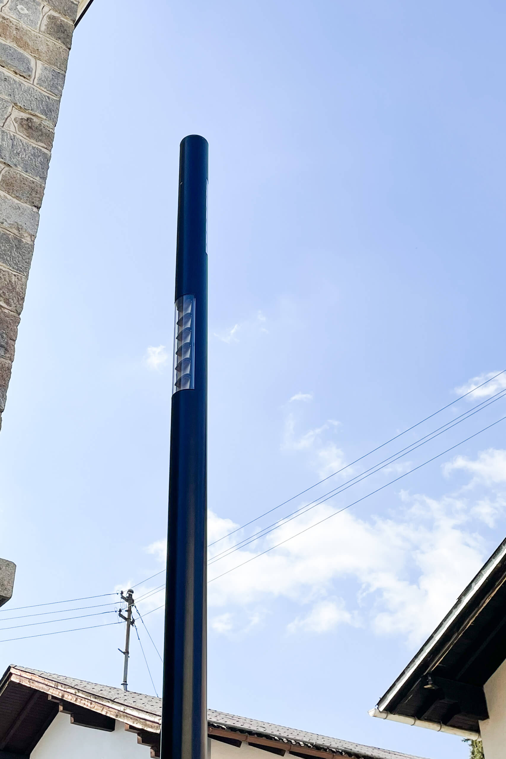 Moderne dunkle Säulenleuchte mit Lichtfenster vor blauem Himmel