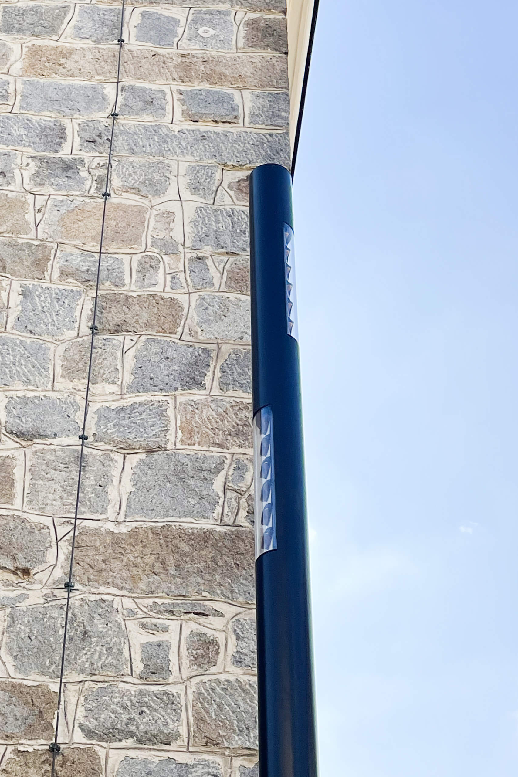 Moderne Außenleuchte beleuchtet eine Steinwand bei Tag.