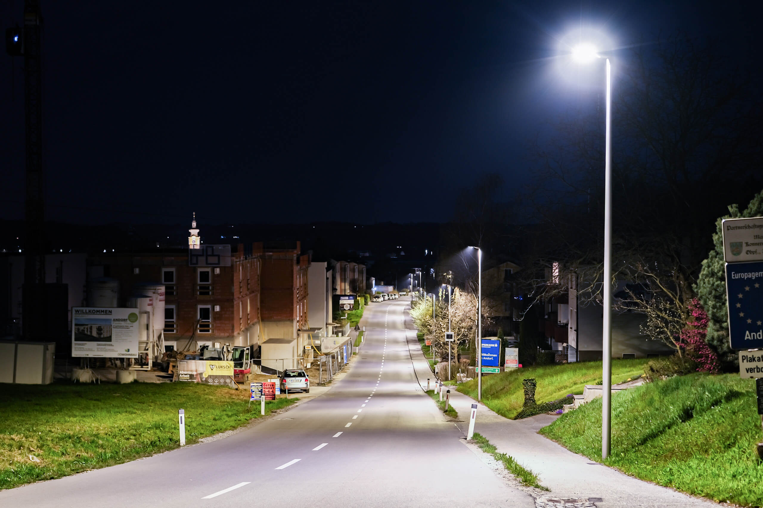 Straßenbeleuchtung in einer Siedlung bei Nacht, beleuchtet durch eine moderne Lampe.