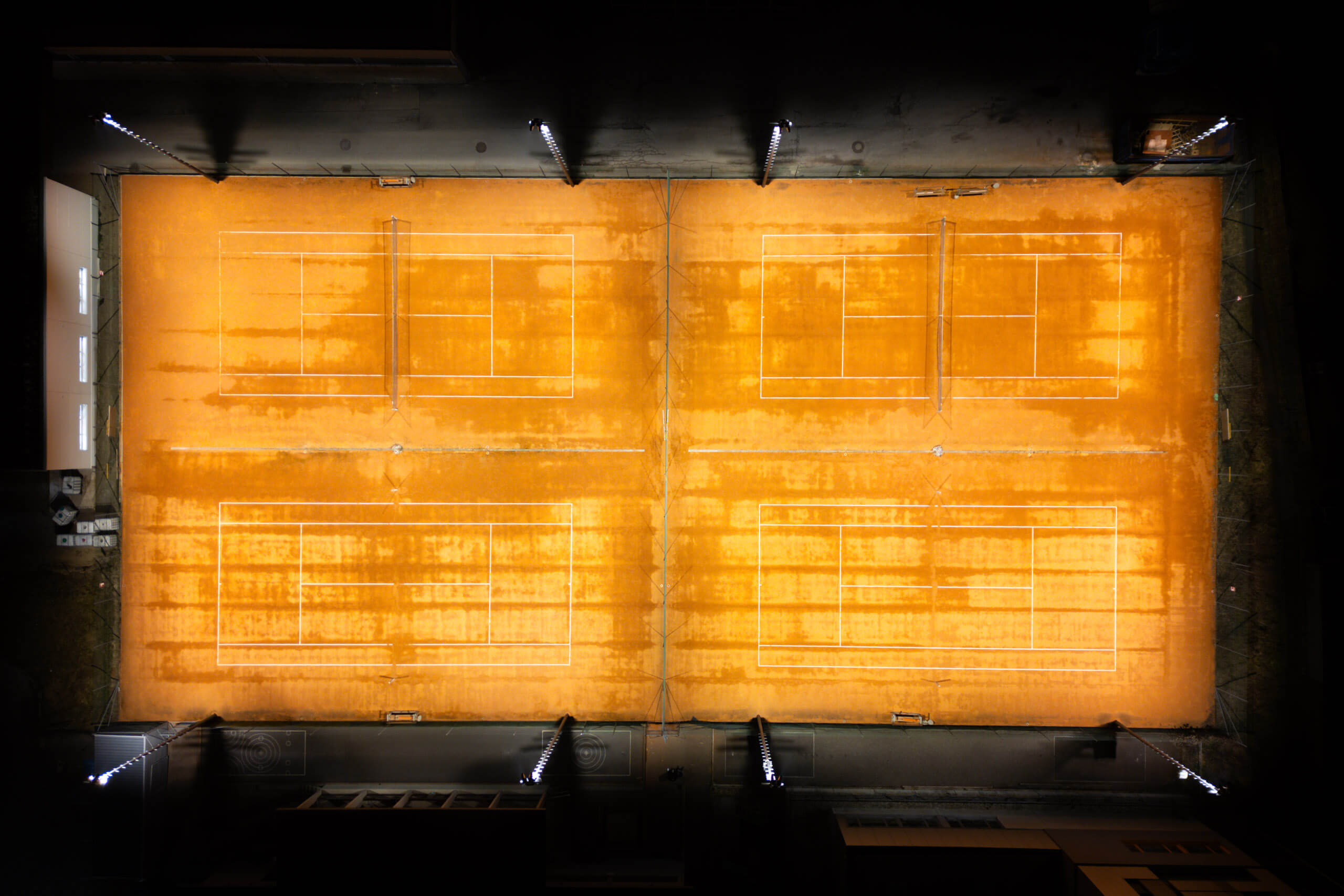 Tennisplätze bei Nacht, beleuchtet durch moderne Scheinwerfer – Lichtplanung von Illumina.