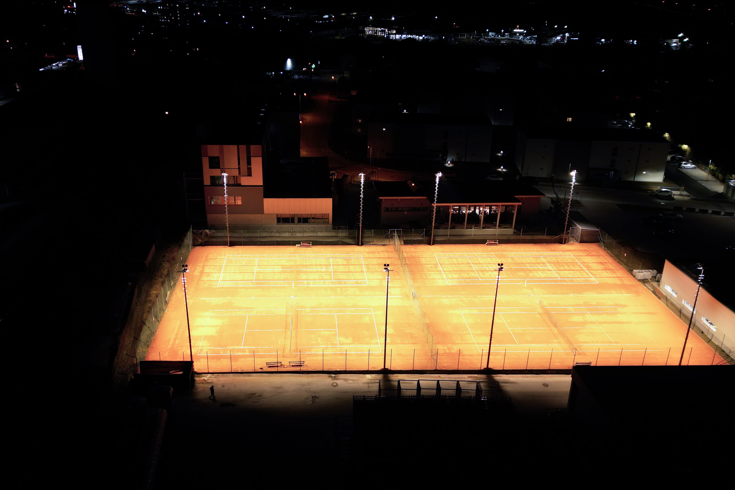 Tennisplätze bei Nacht, beleuchtet von modernen Sportplatzleuchten.