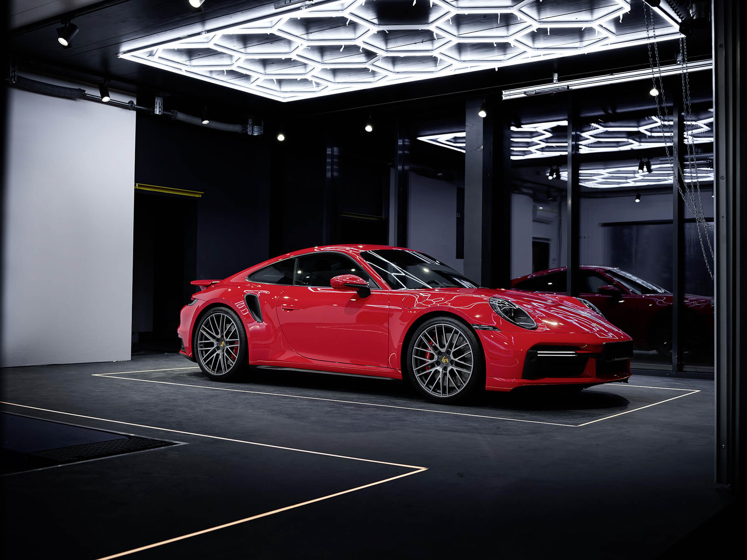 Roter Porsche 911 Turbo S in modernem Showroom mit akzentuierter Deckenbeleuchtung