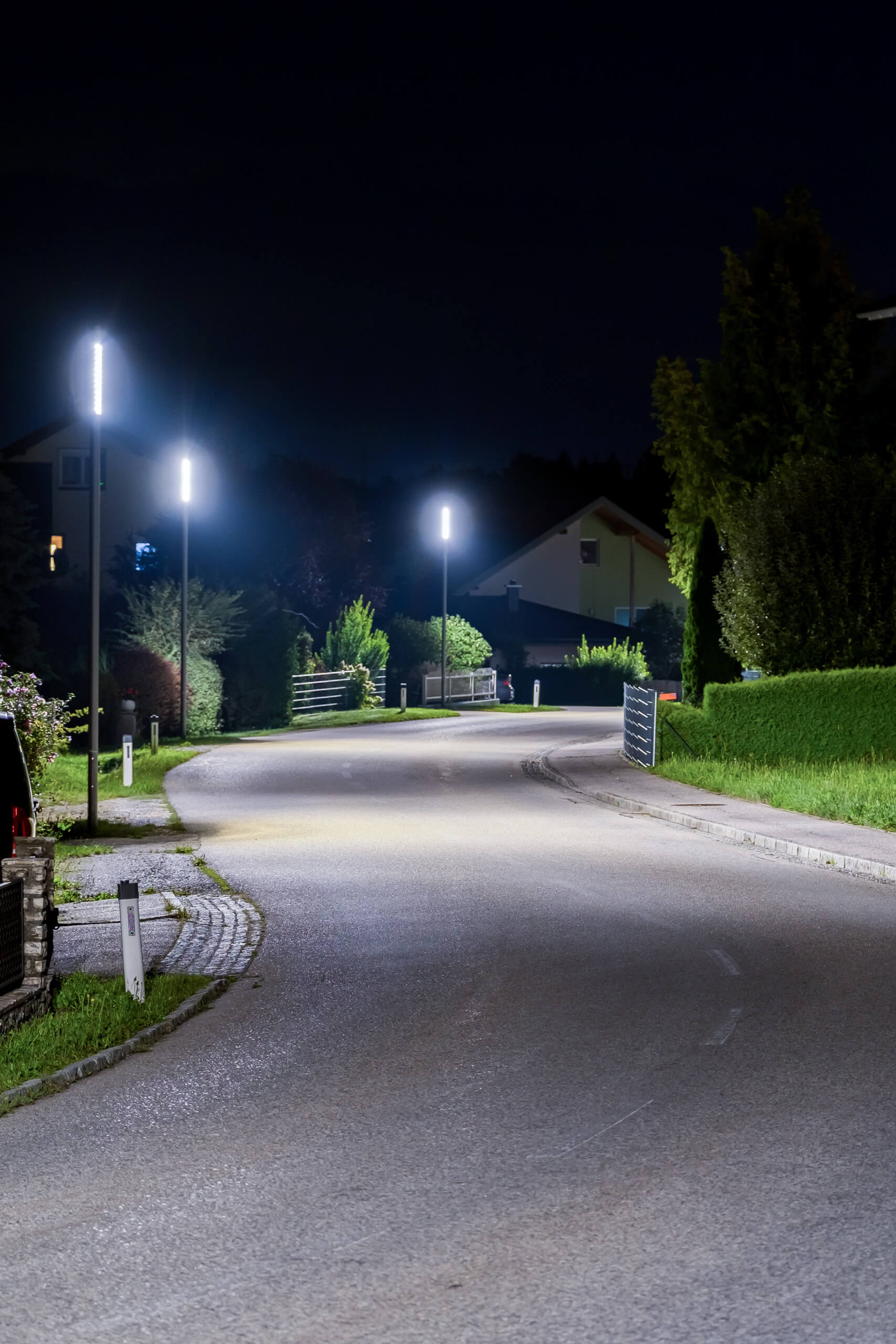 Beleuchtete Straße in einem Wohngebiet bei Nacht mit modernen Straßenlaternen von Illumina.