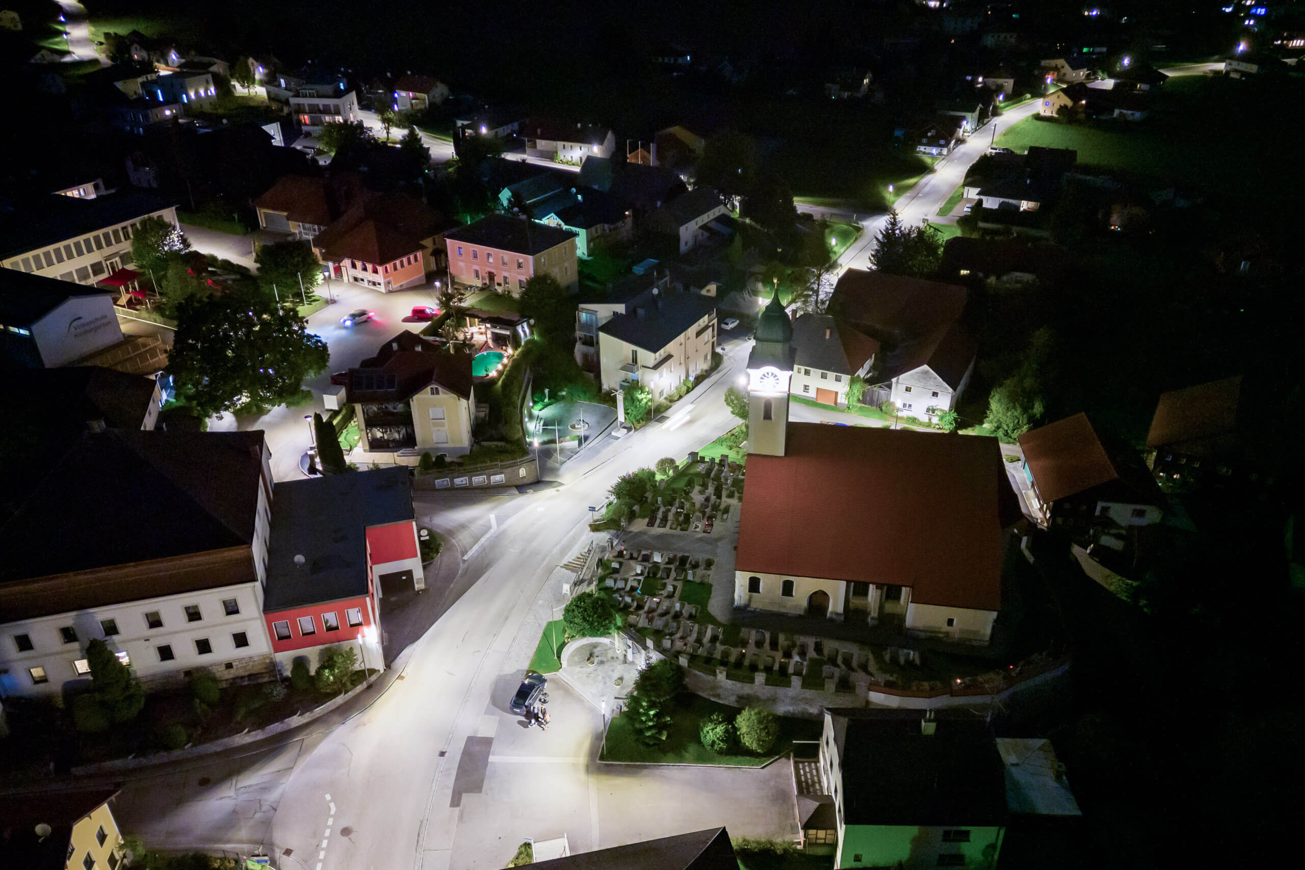 Nachtaufnahme eines Dorfes mit Kirche und Straßenbeleuchtung