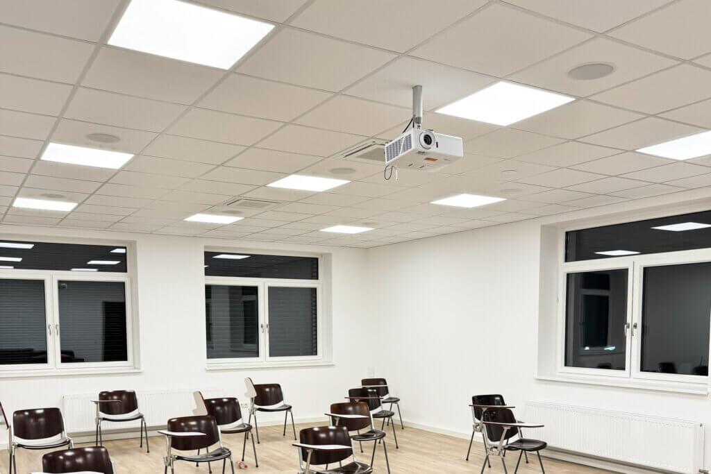 Helles Klassenzimmer mit moderner Beamer-Installation und Sitzreihen