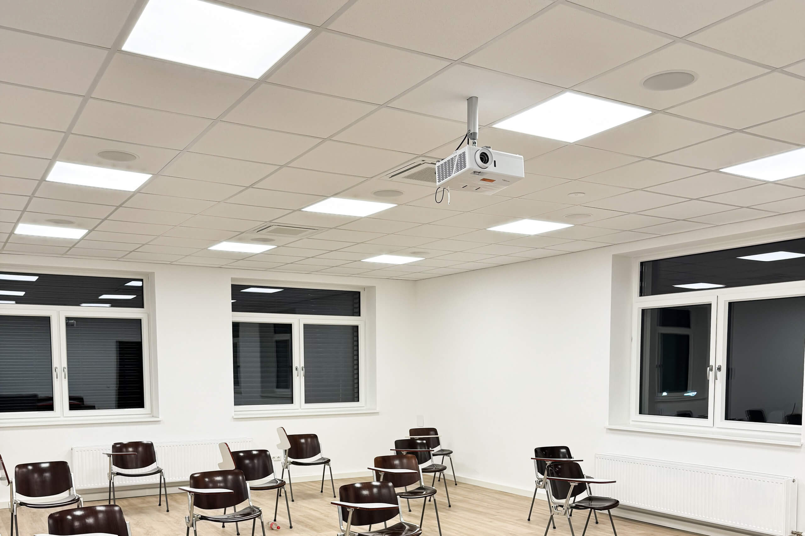 Helles Klassenzimmer mit moderner Beamer-Installation und Sitzreihen