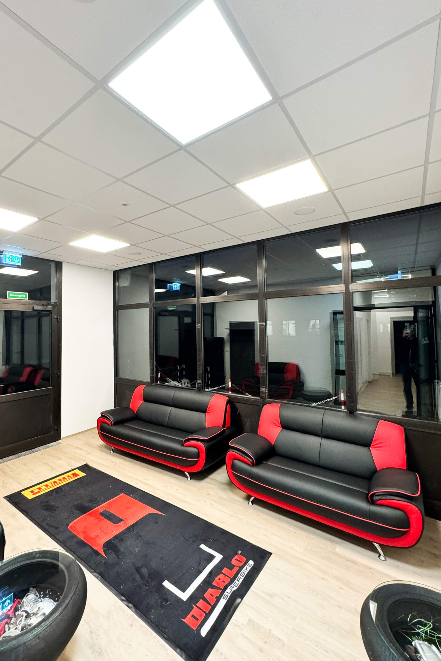 Moderne Werkstatt-Lounge mit zwei roten und schwarzen Sofas und Pirelli-Matte.