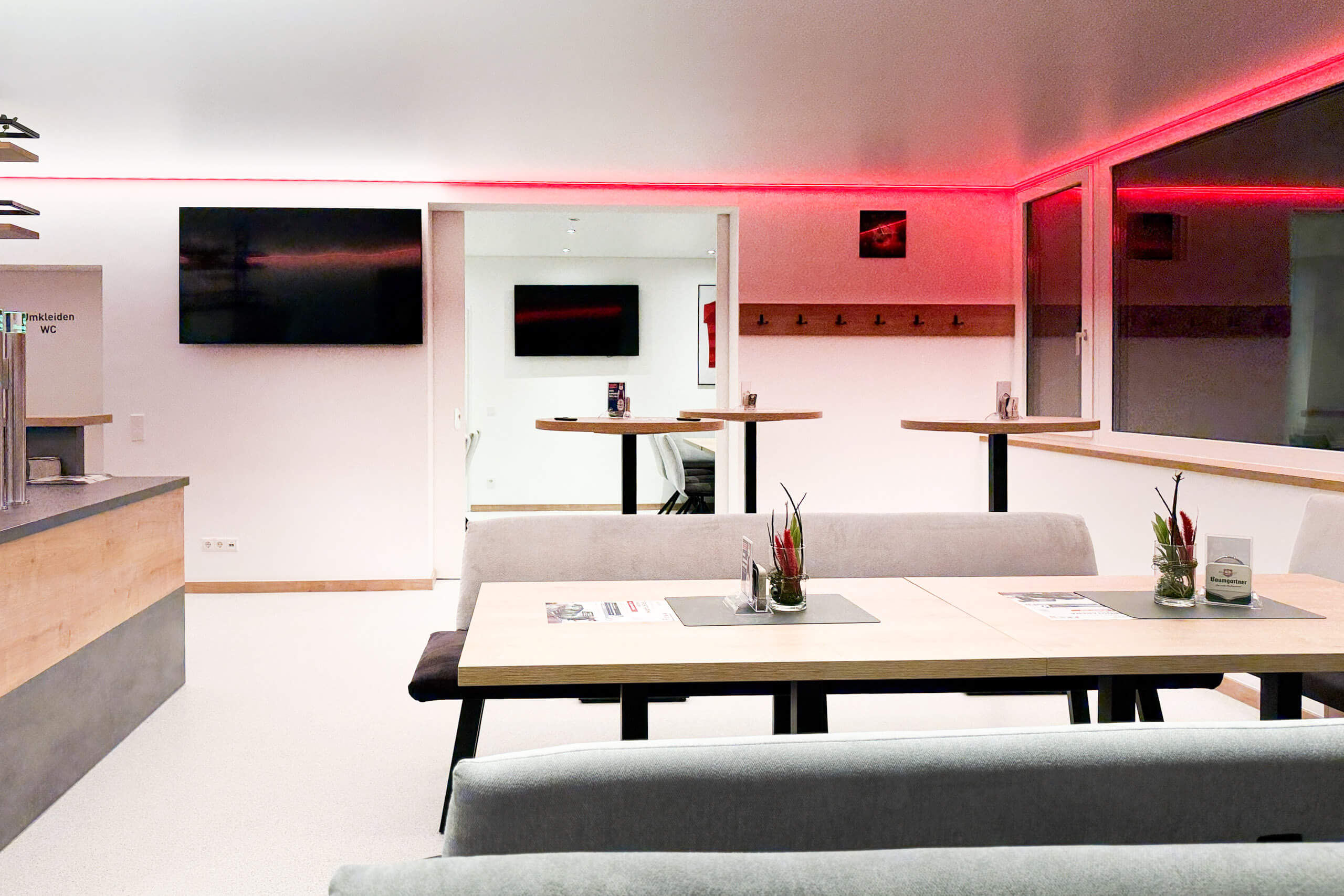 Moderner Loungebereich mit Bartischen und Sitzgruppen, stimmungsvoll beleuchtet mit rotem LED-Licht.