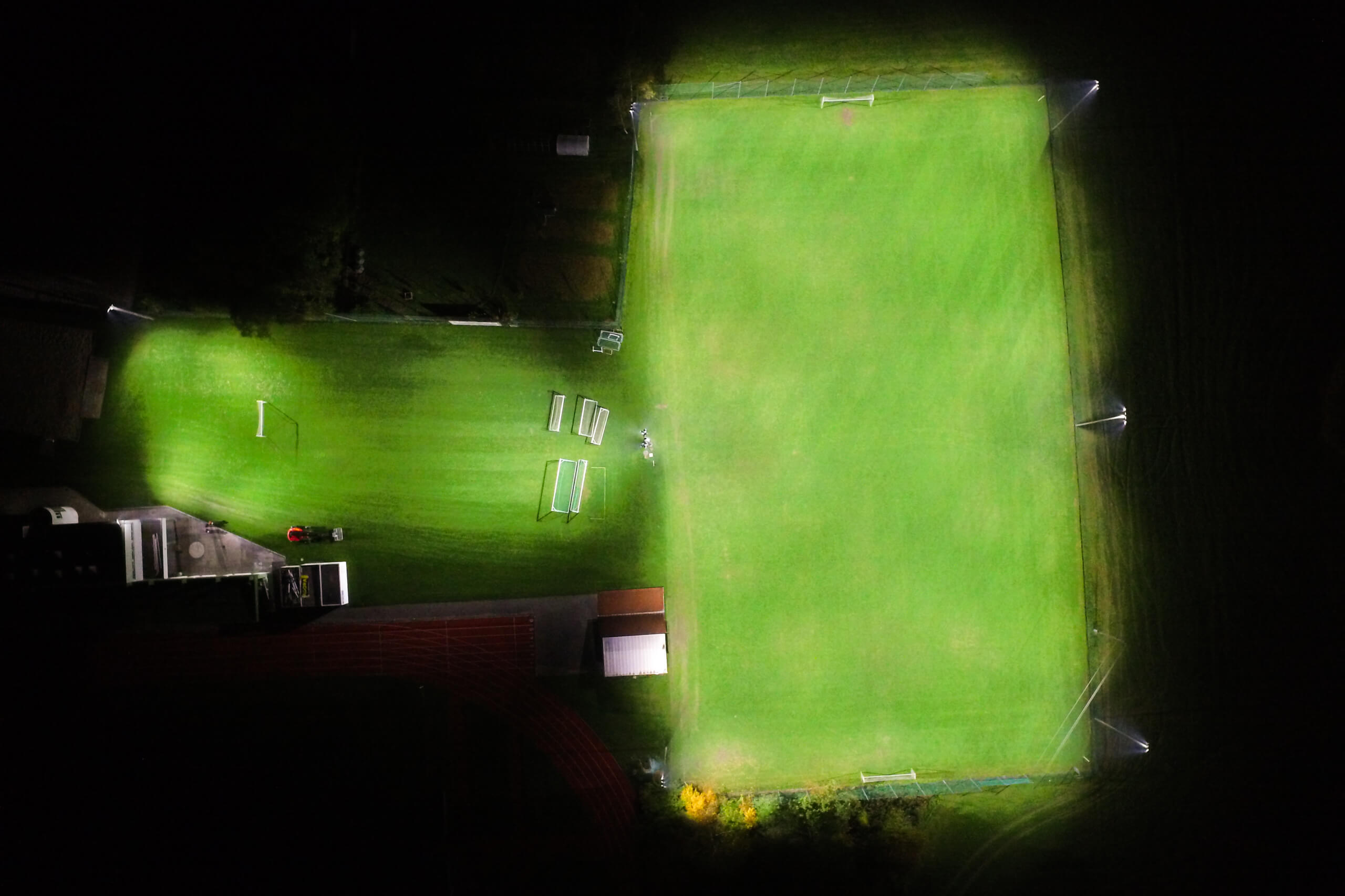 Beleuchteter Sportplatz mit Rasen und Laufbahn bei Nacht, Lichtplanung von Illumina.