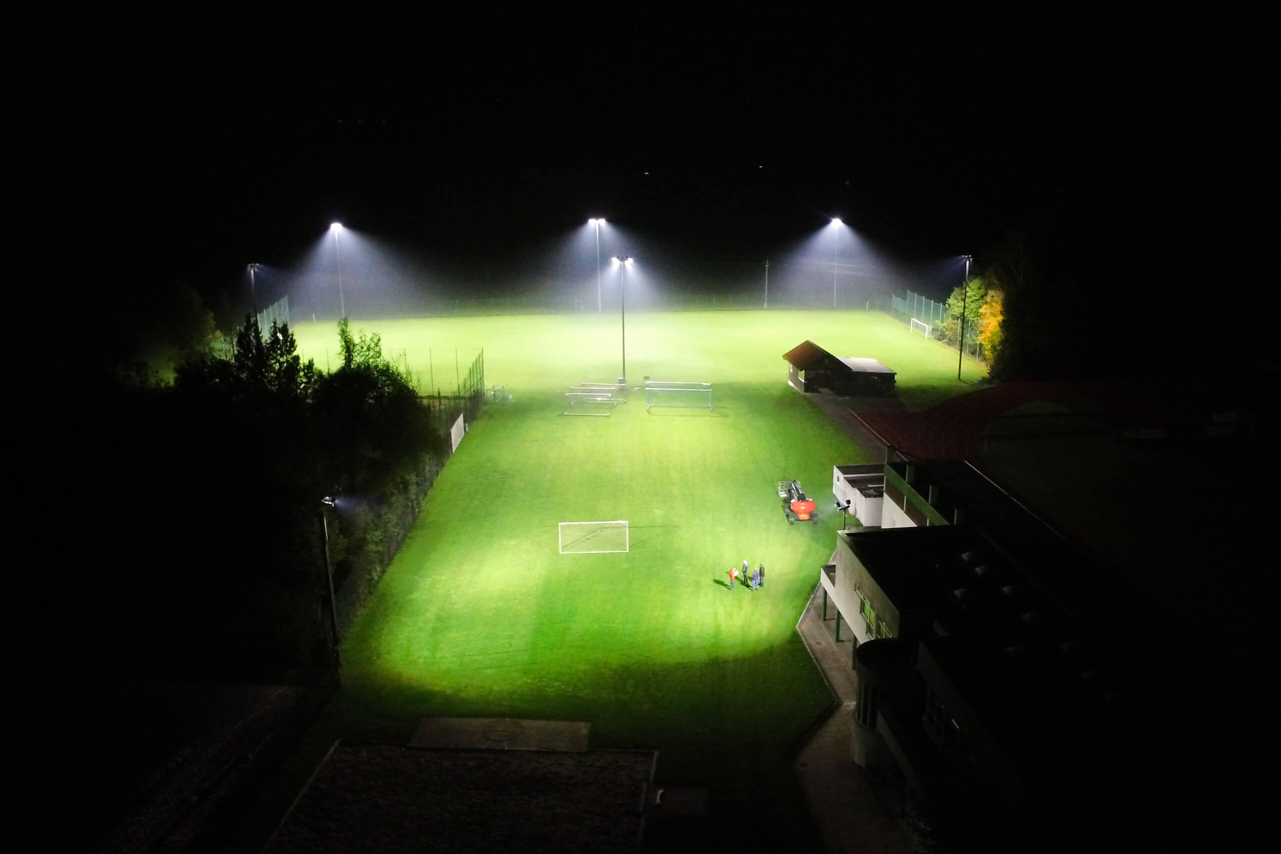 Fußballplatzbeleuchtung von Illumina: Rasenplatz mit Flutlicht und Traktor bei Nacht.