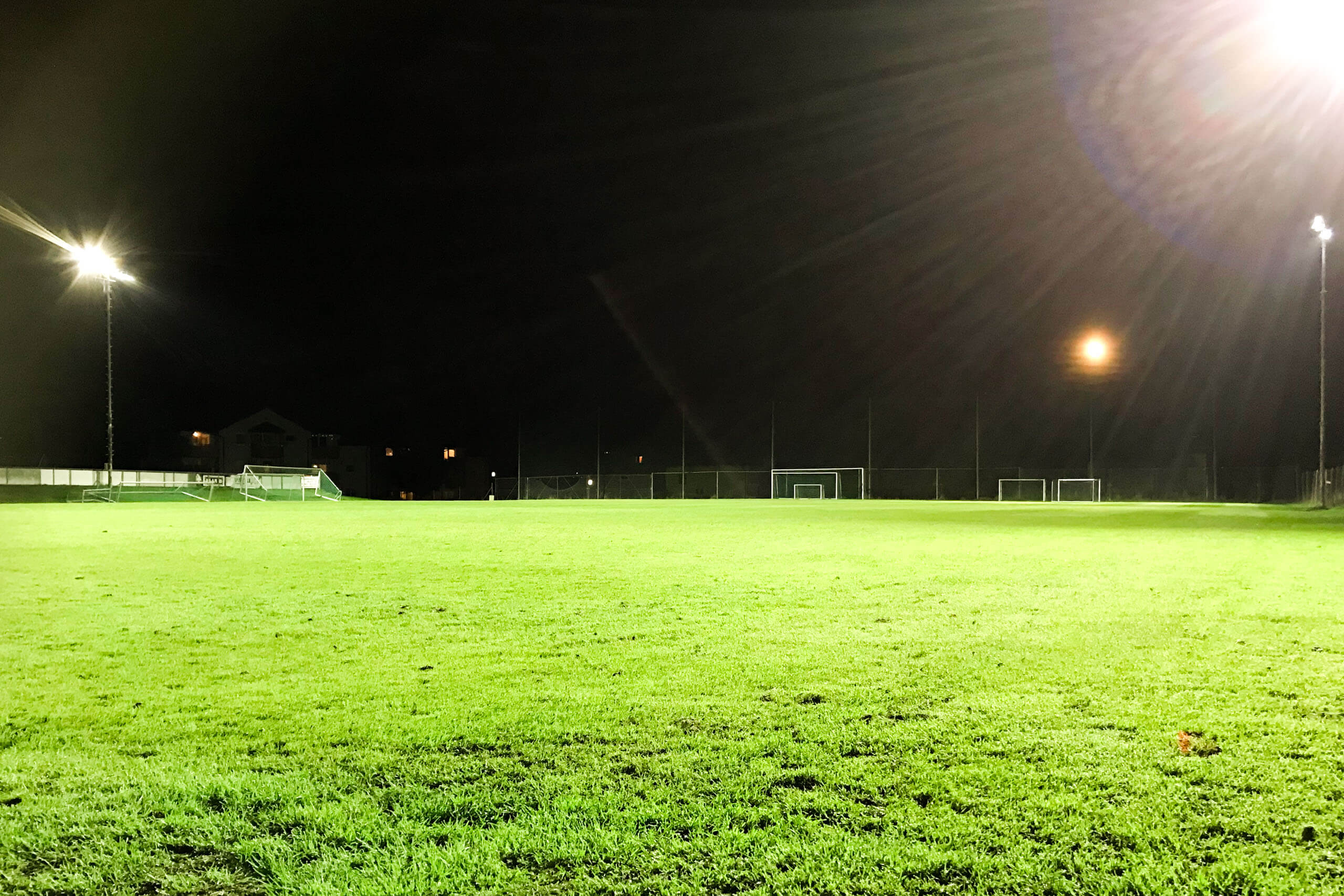 Fußballplatz mit Flutlichtbeleuchtung bei Nacht