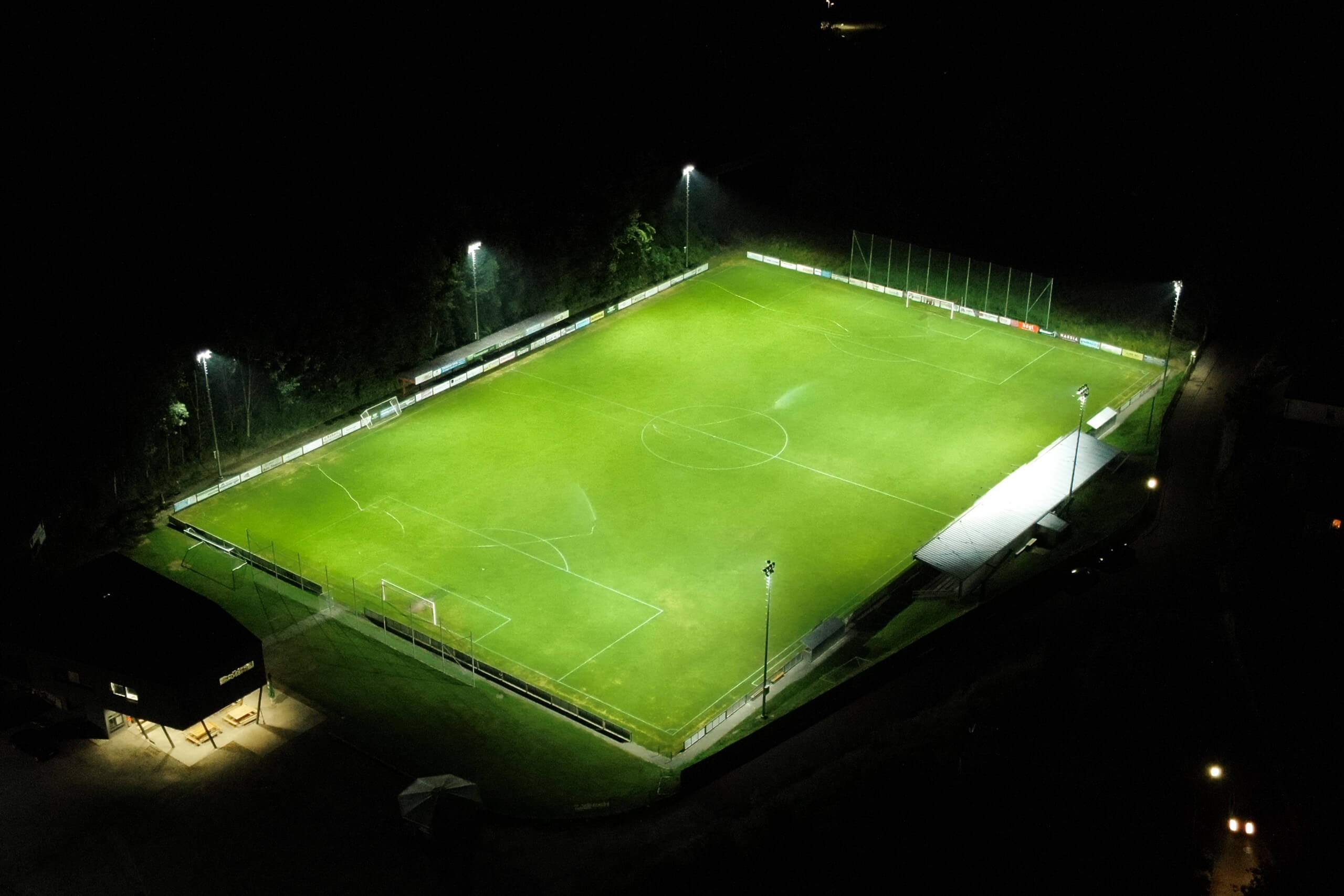 Sportplatzbeleuchtung bei Nacht mit grünem Rasen und hellen Lichtern von Illumina