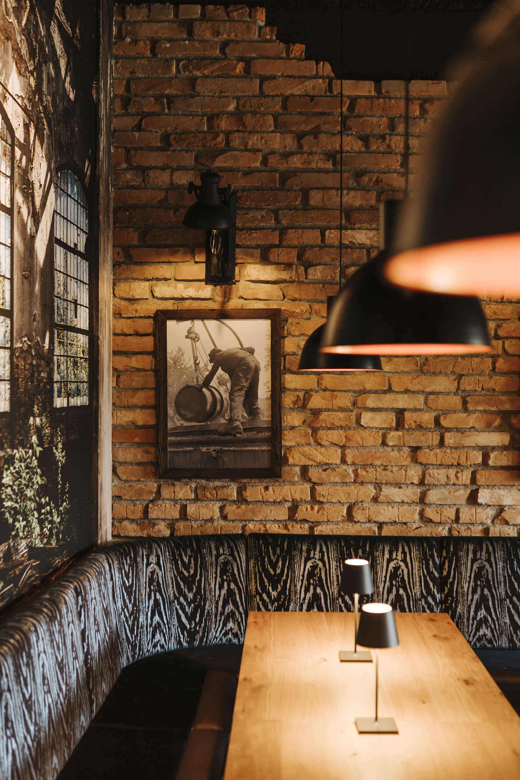 Gewerbliche Lichtplanung: Gemütliche Bar mit Ziegelwand, Holztisch und stimmungsvoller Beleuchtung