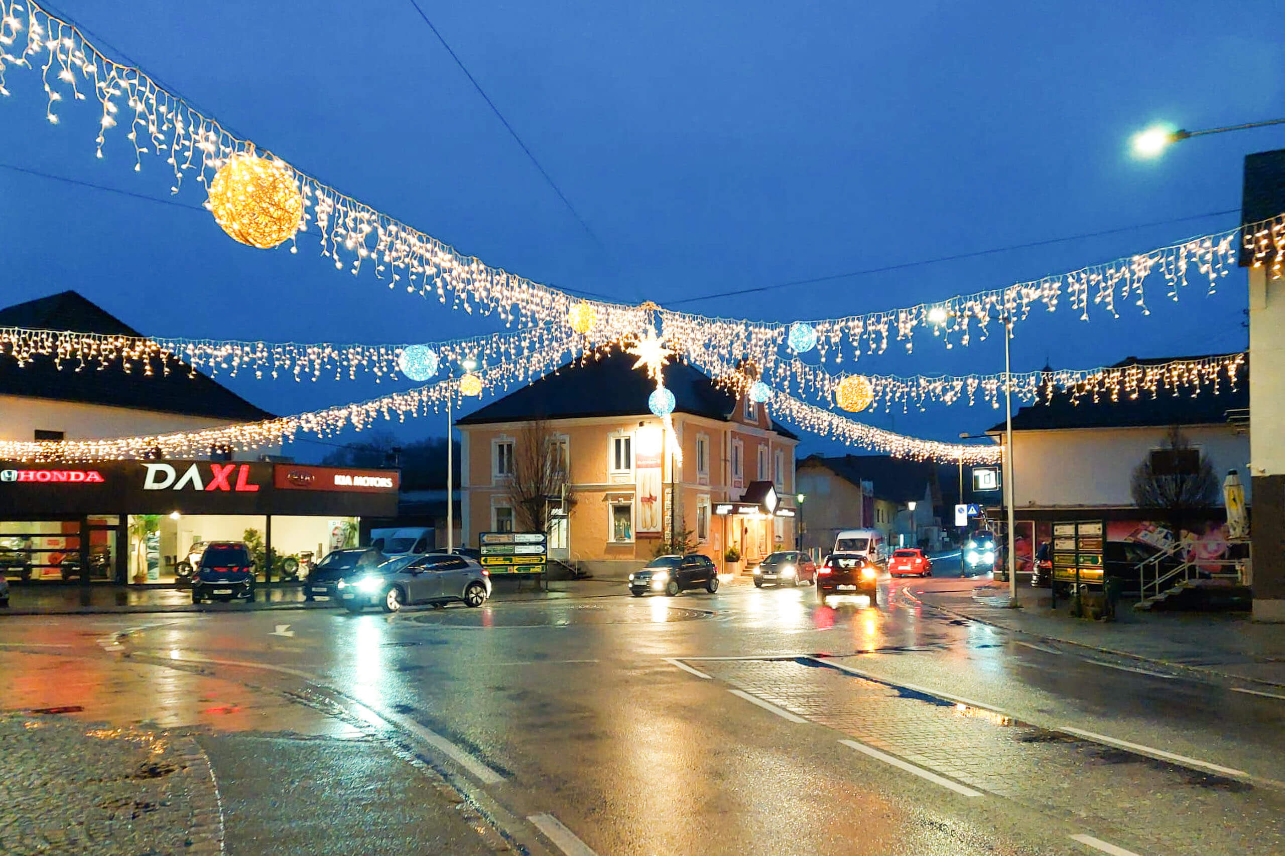 Straßenbeleuchtung im Dunkeln mit Weihnachtsdeko und Autoverkehr