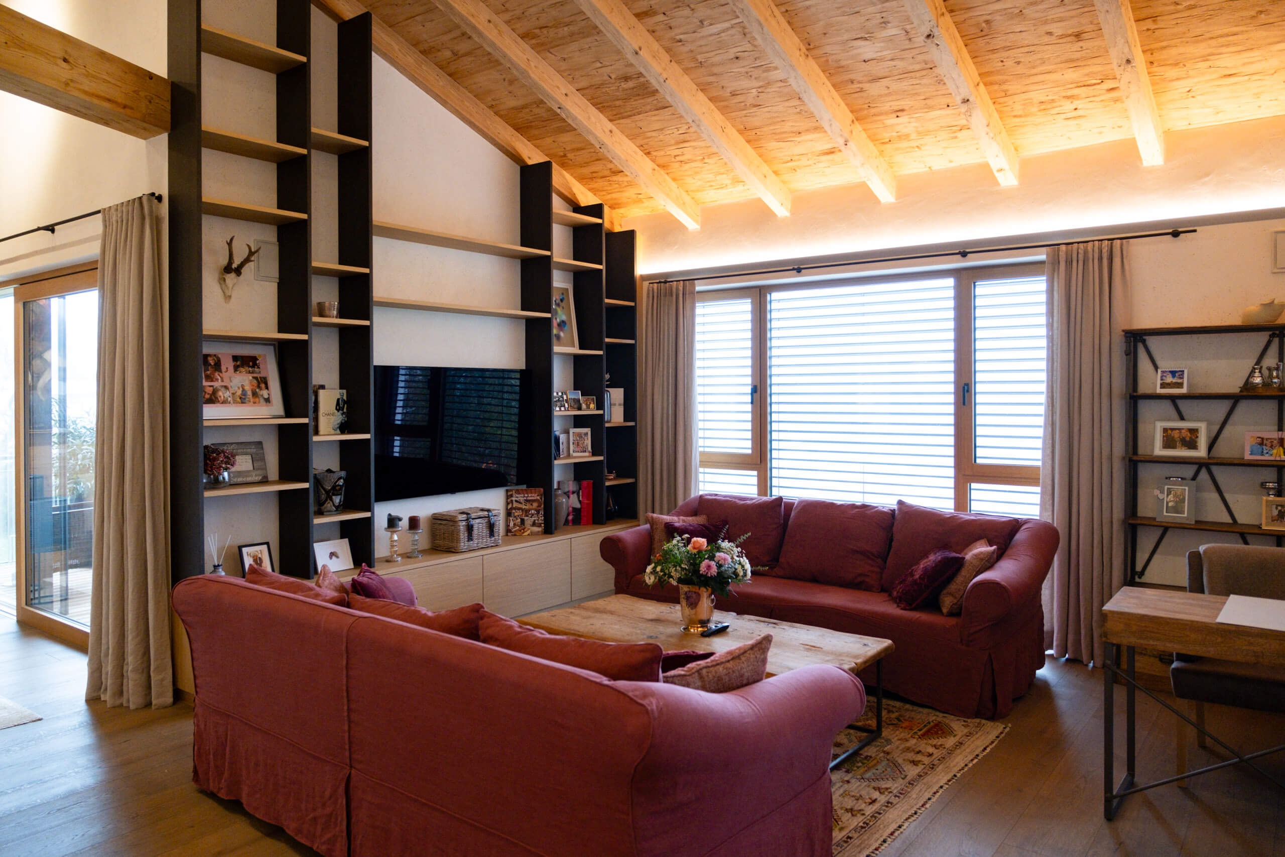 Gemütliches Wohnzimmer mit Holzbalkendecke, Kamin und Sitzmöbeln.