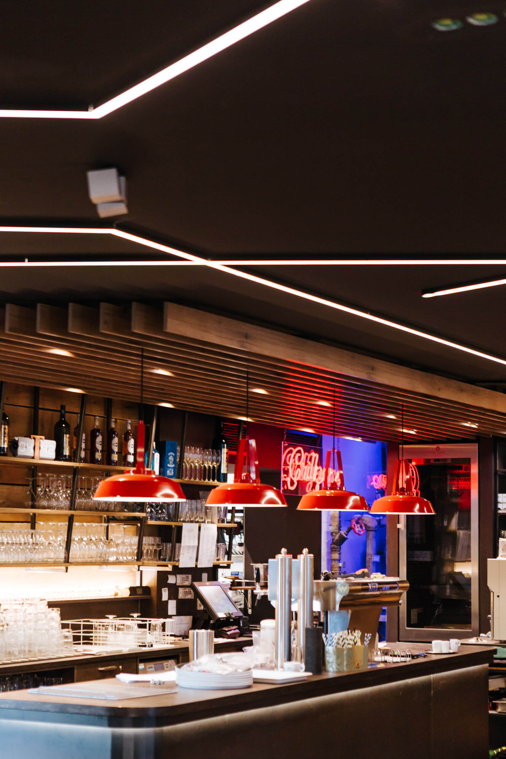 Gewerbe-Lichtberechnung: Moderne Bar mit roten Hängeleuchten und Neonreklame