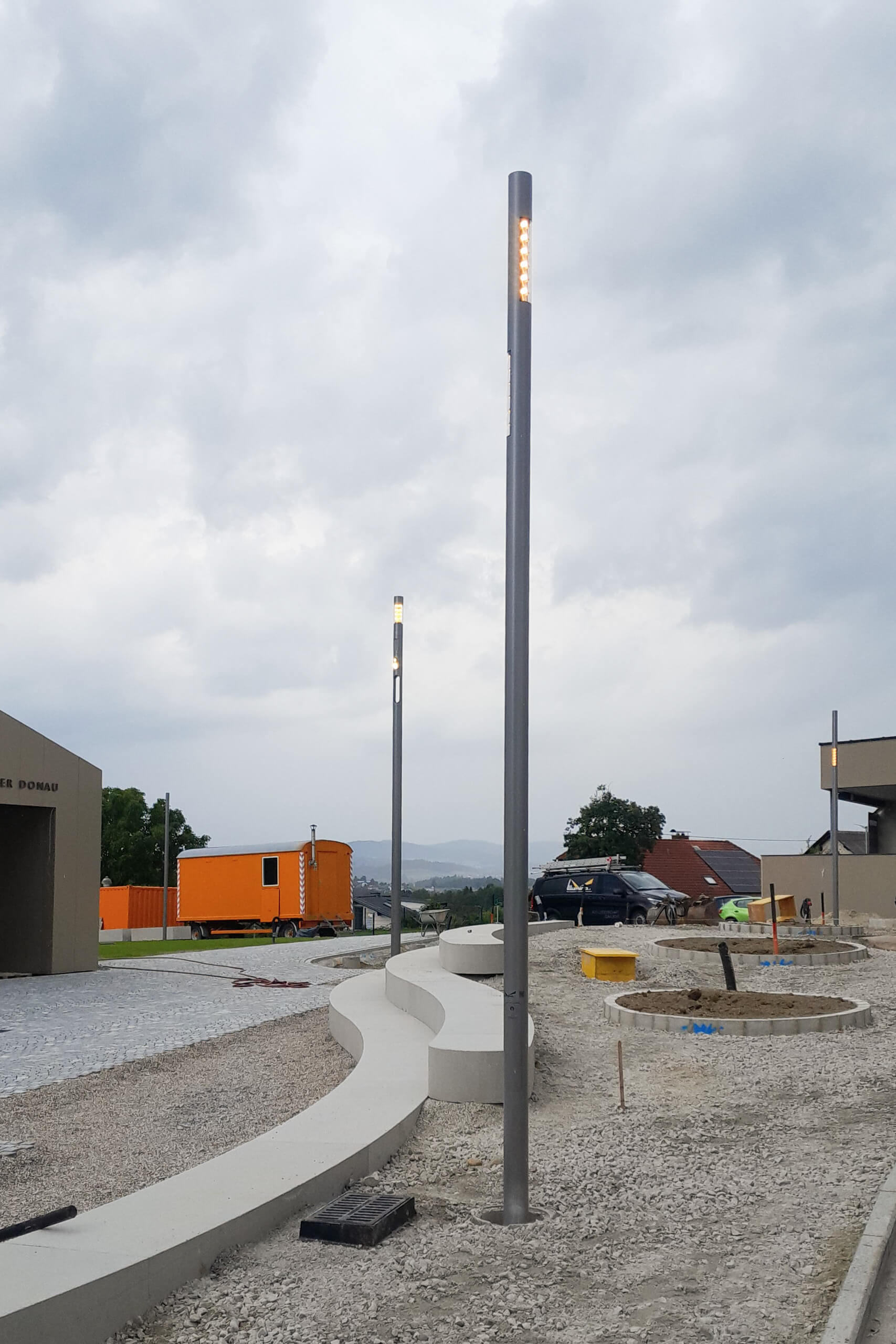 Moderne Straßenlaternen und Sitzbank im Außenbereich – Lichtplanung von Illumina.