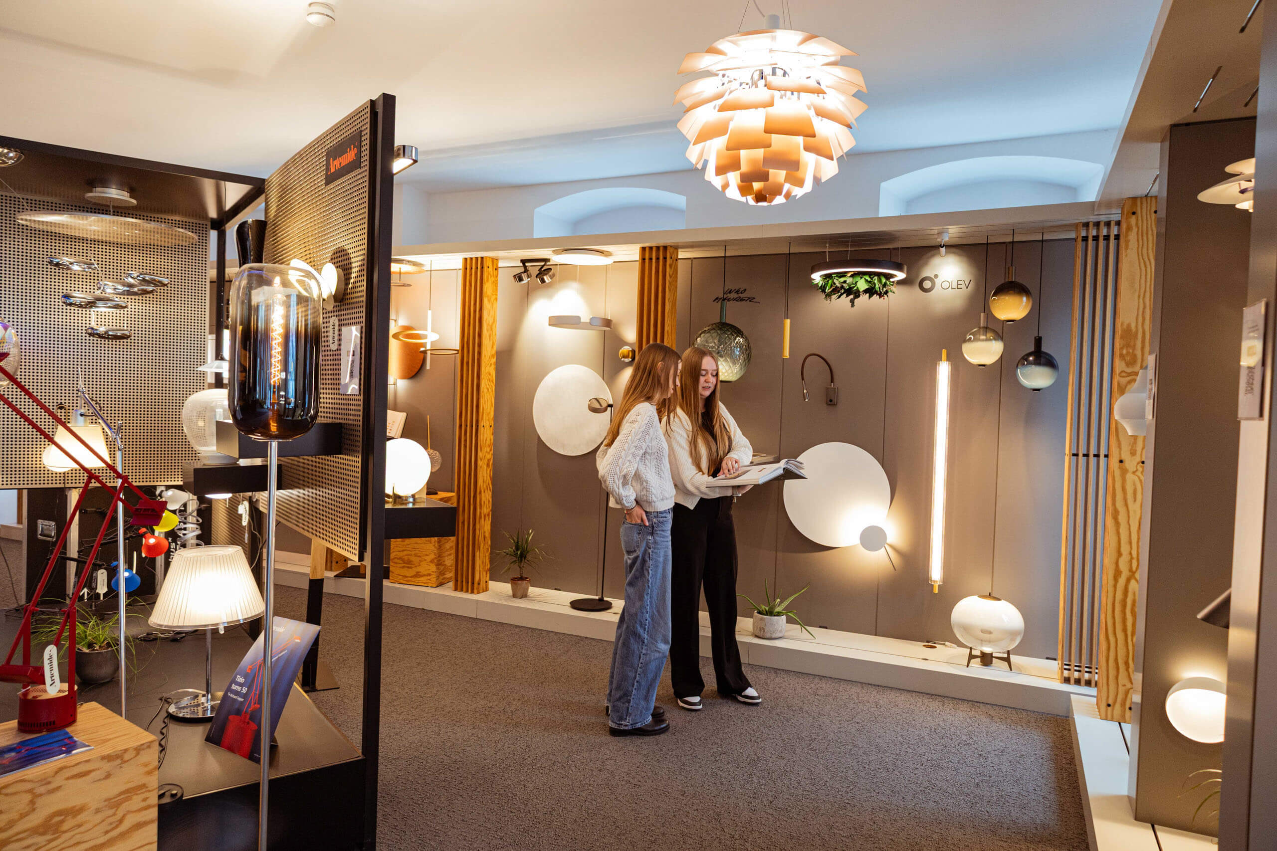 Zwei Frauen in einem Showroom mit modernen Leuchten, die sich über Lichtplanung informieren.