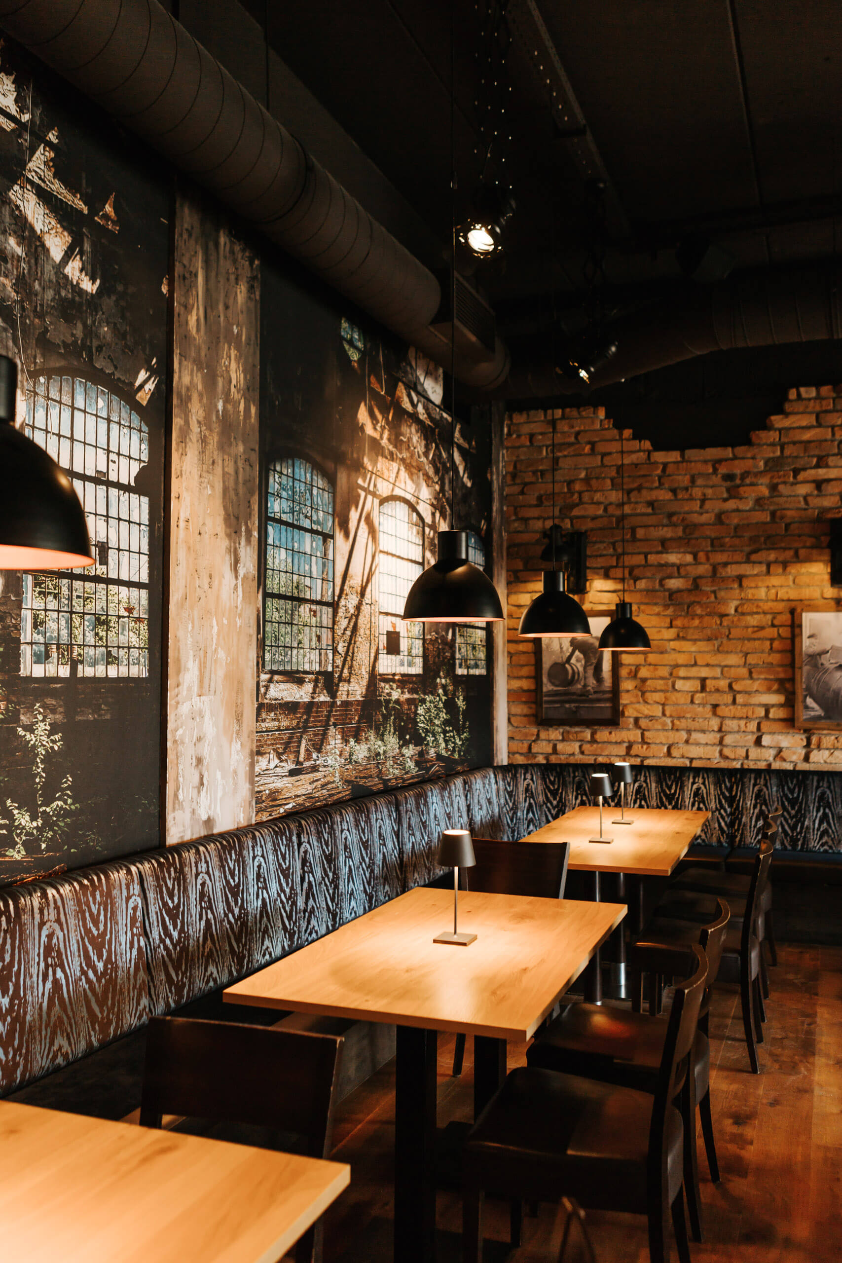 Gemütliches Restaurant-Ambiente mit Holztischen und Ziegelwand – Lichtplanung von Illumina.