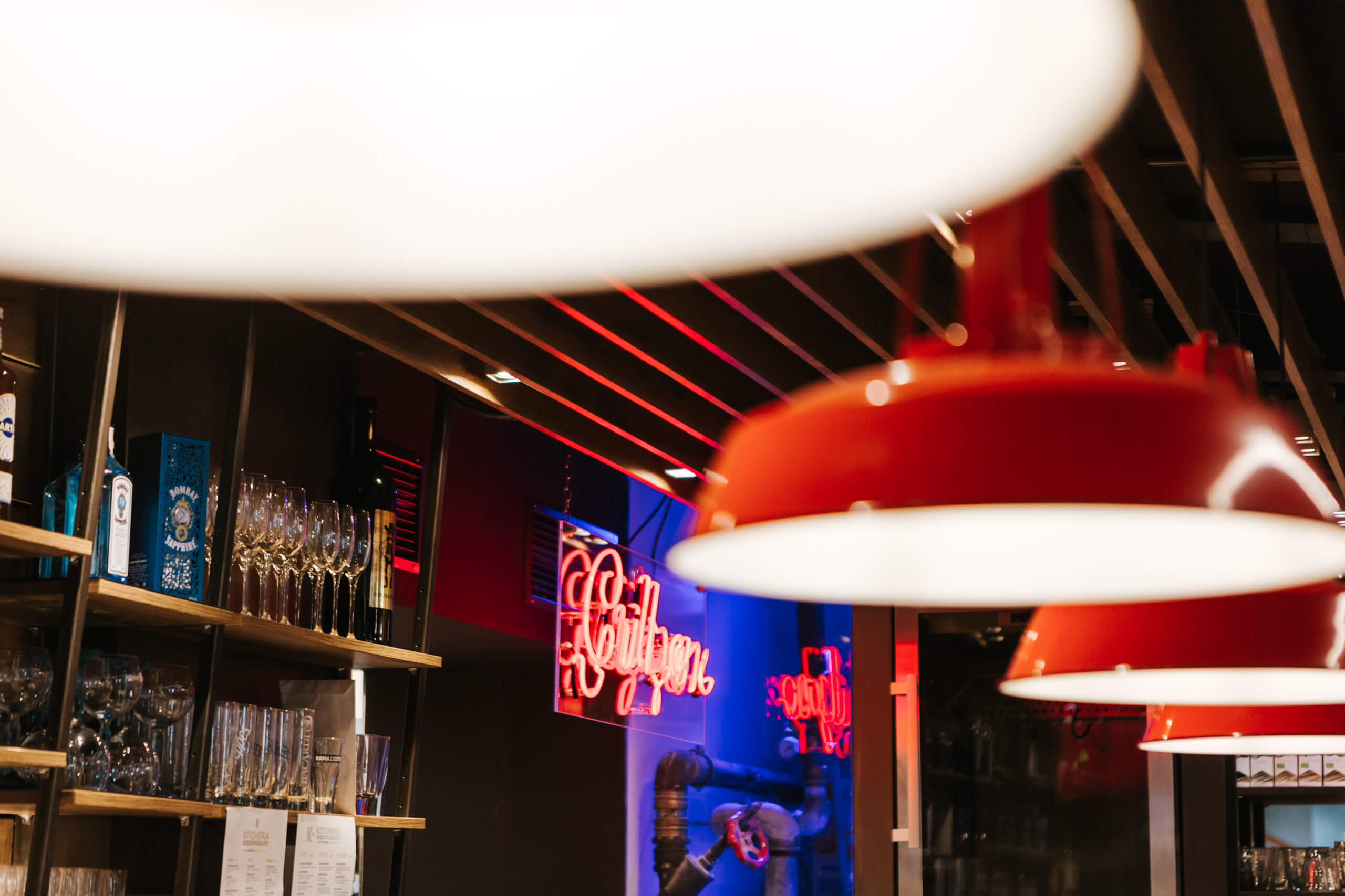 Rote Lampenschirme und Neonlicht in einer Bar, Lichtplanung von Illumina.