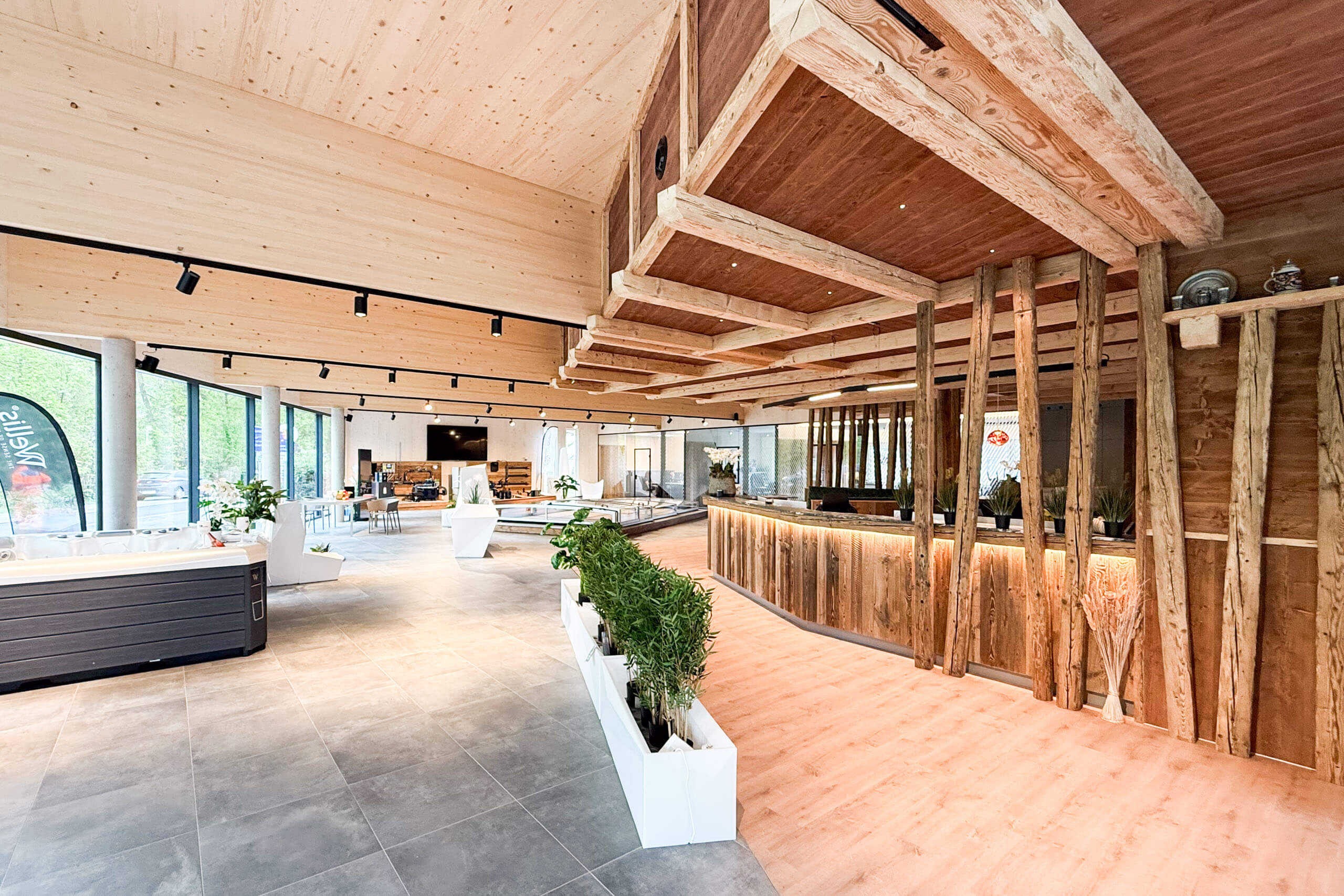Helle, moderne Holzbau-Lounge mit Sitzbereichen und Pflanzen – Lichtplanung von Illumina.