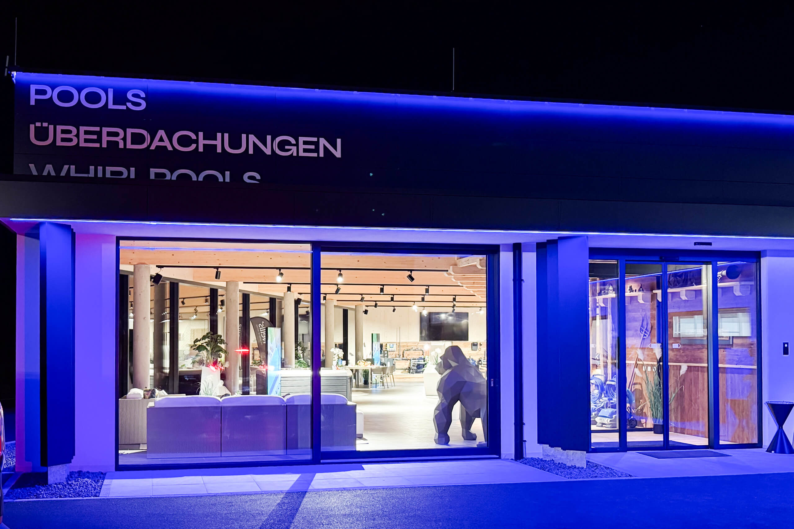 Moderne Fassade eines Geschäfts für Pools und Überdachungen mit auffälliger blauer Beleuchtung