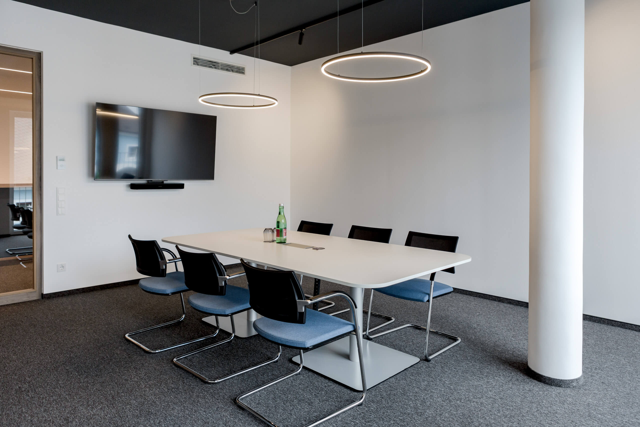 Moderne Besprechungsraumbeleuchtung mit kreisförmigen Pendelleuchten von Illumina.