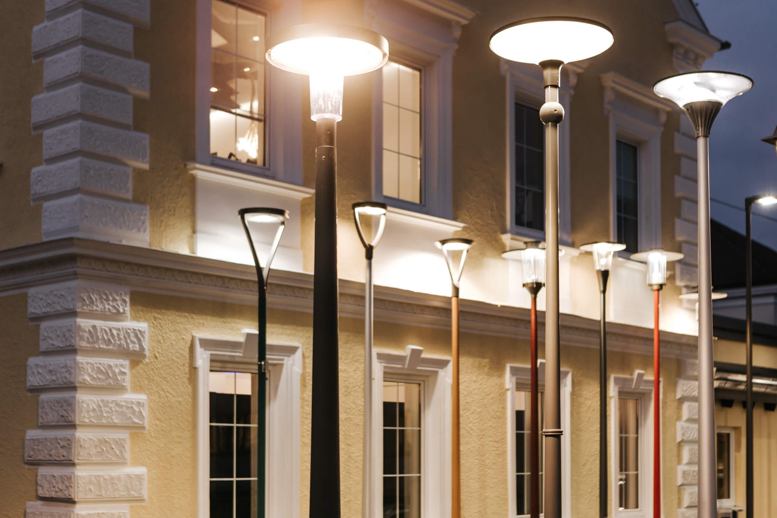 Illumina: Moderne Straßenlaternen beleuchten ein historisches Gebäude bei Nacht.