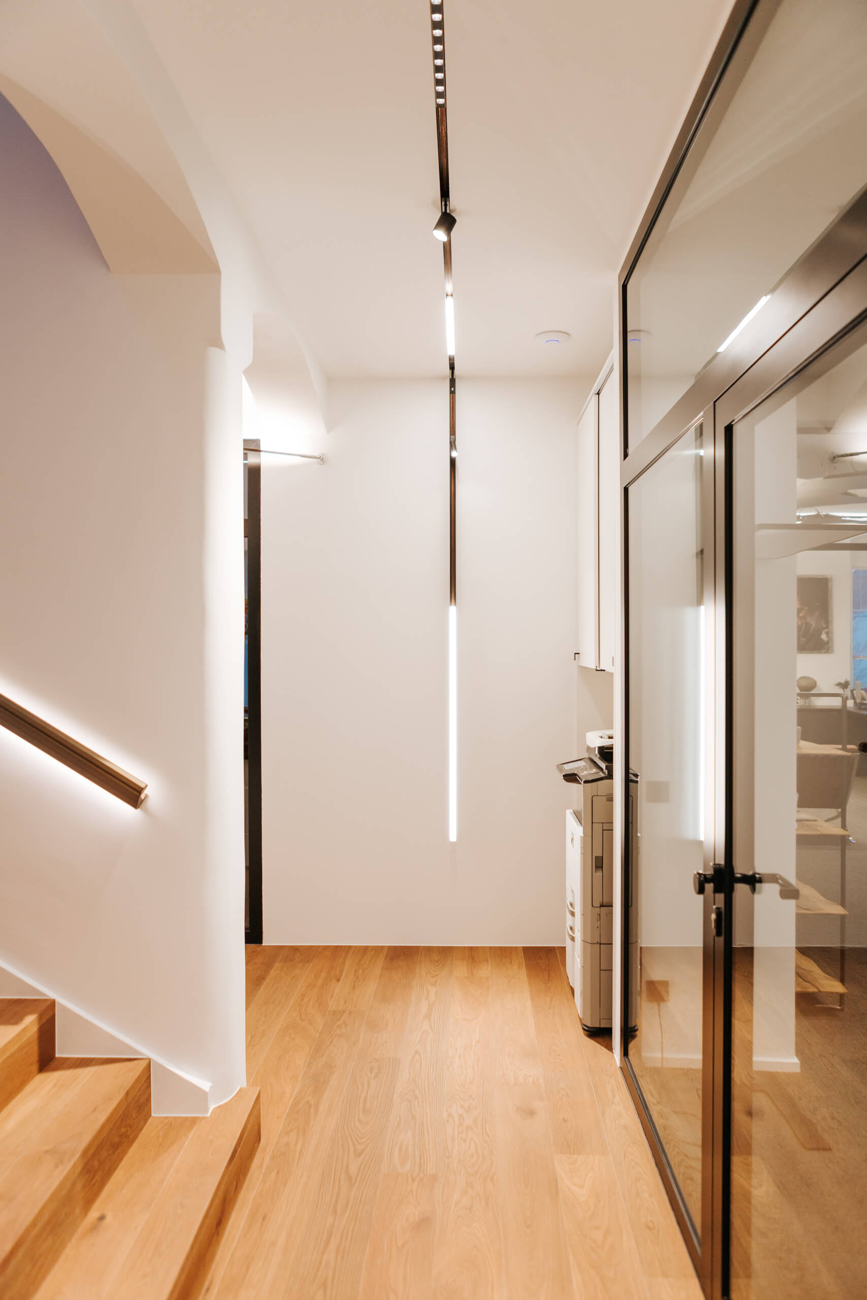Heller Flur mit Holztreppe und moderner Beleuchtung im Lichtstudio Oberösterreich.