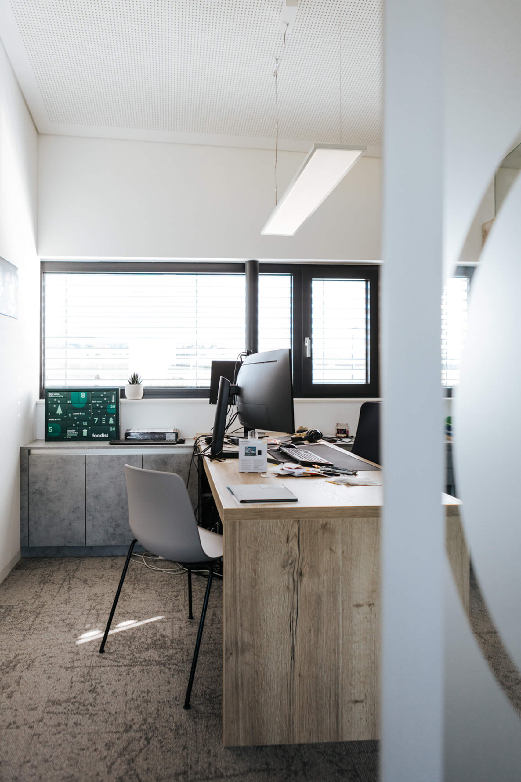 Beleuchtetes Büro mit Schreibtisch, Monitor und Fenster – Lichtplanung von Illumina.