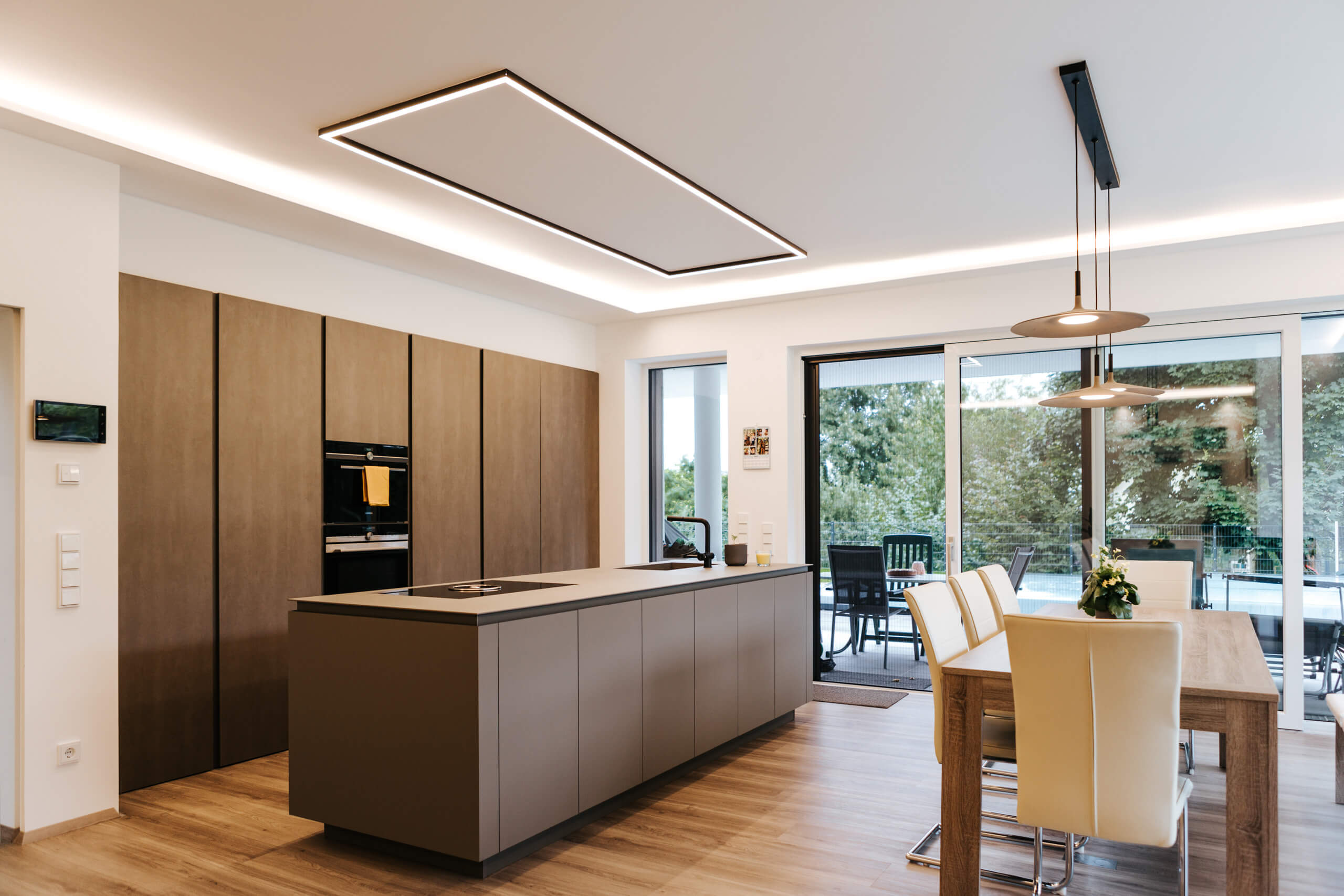 Moderne Küche mit Insel und Essbereich, stimmungsvolle Lichtplanung für Privatkunden.