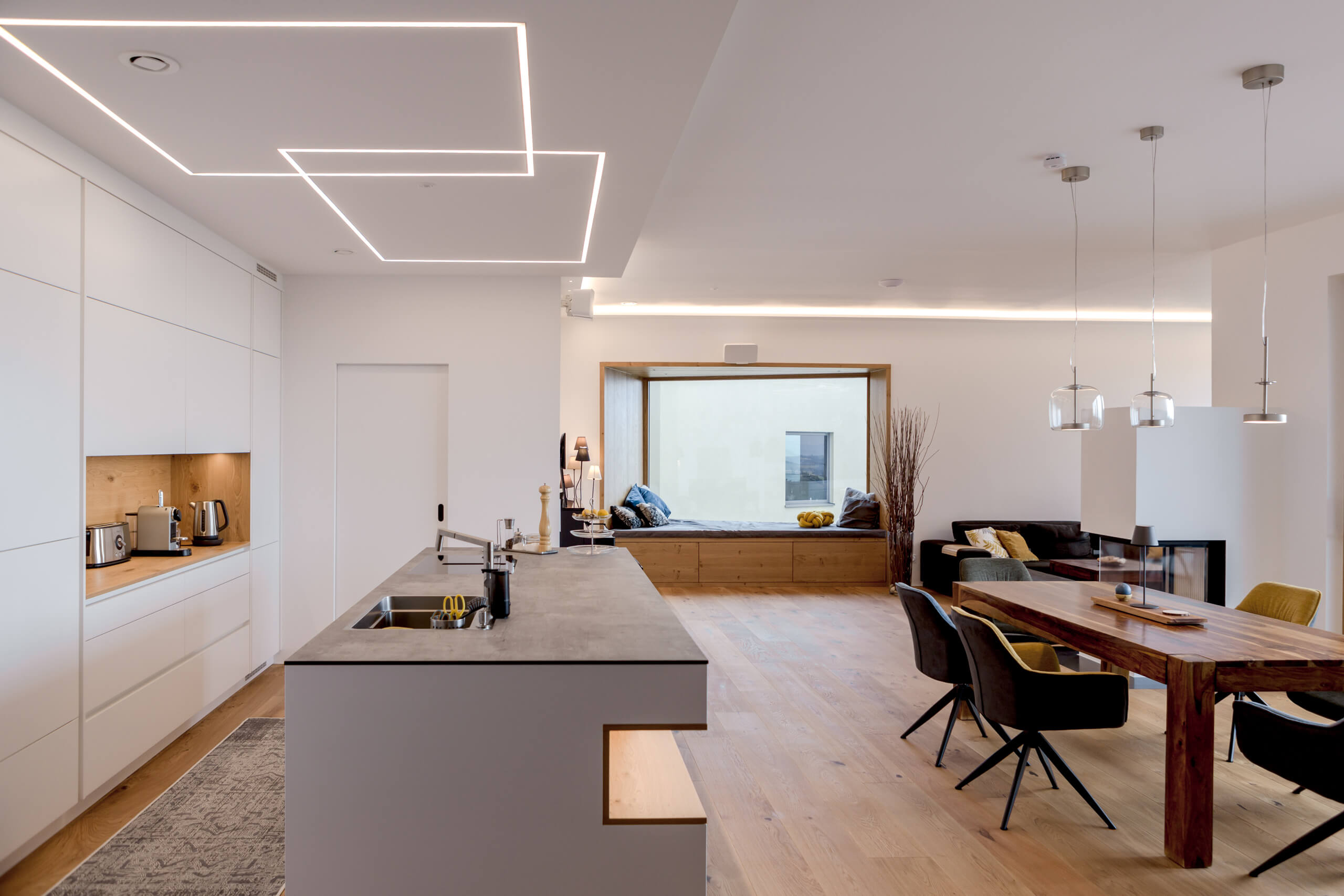 Moderne Wohnküche mit Insel und Essbereich – durchdachte Lichtplanung.