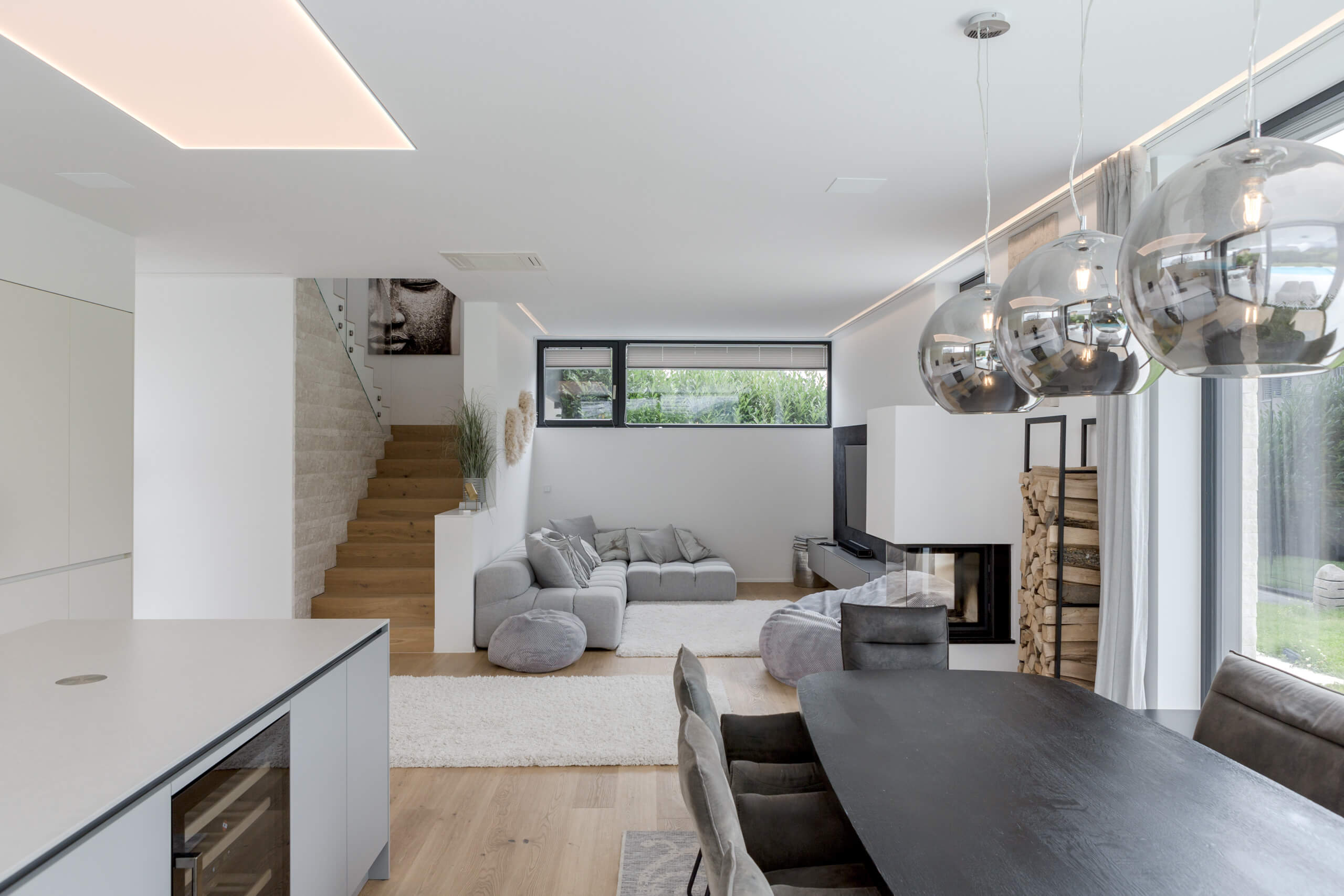 Modernes Wohnzimmer mit eleganten Hängeleuchten und Kamin – Lichtplanung von Illumina.
