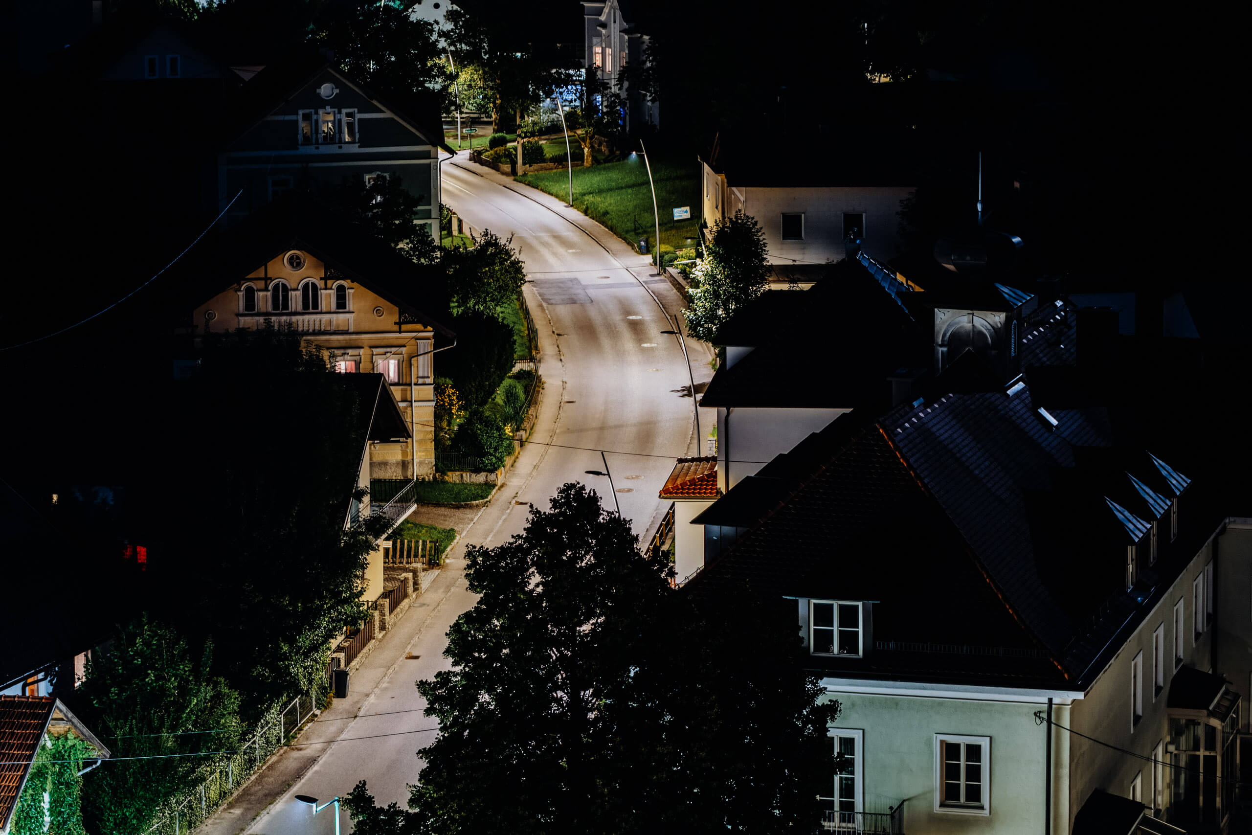 Straßenbeleuchtung erhellt eine ruhige Dorfstraße bei Nacht.