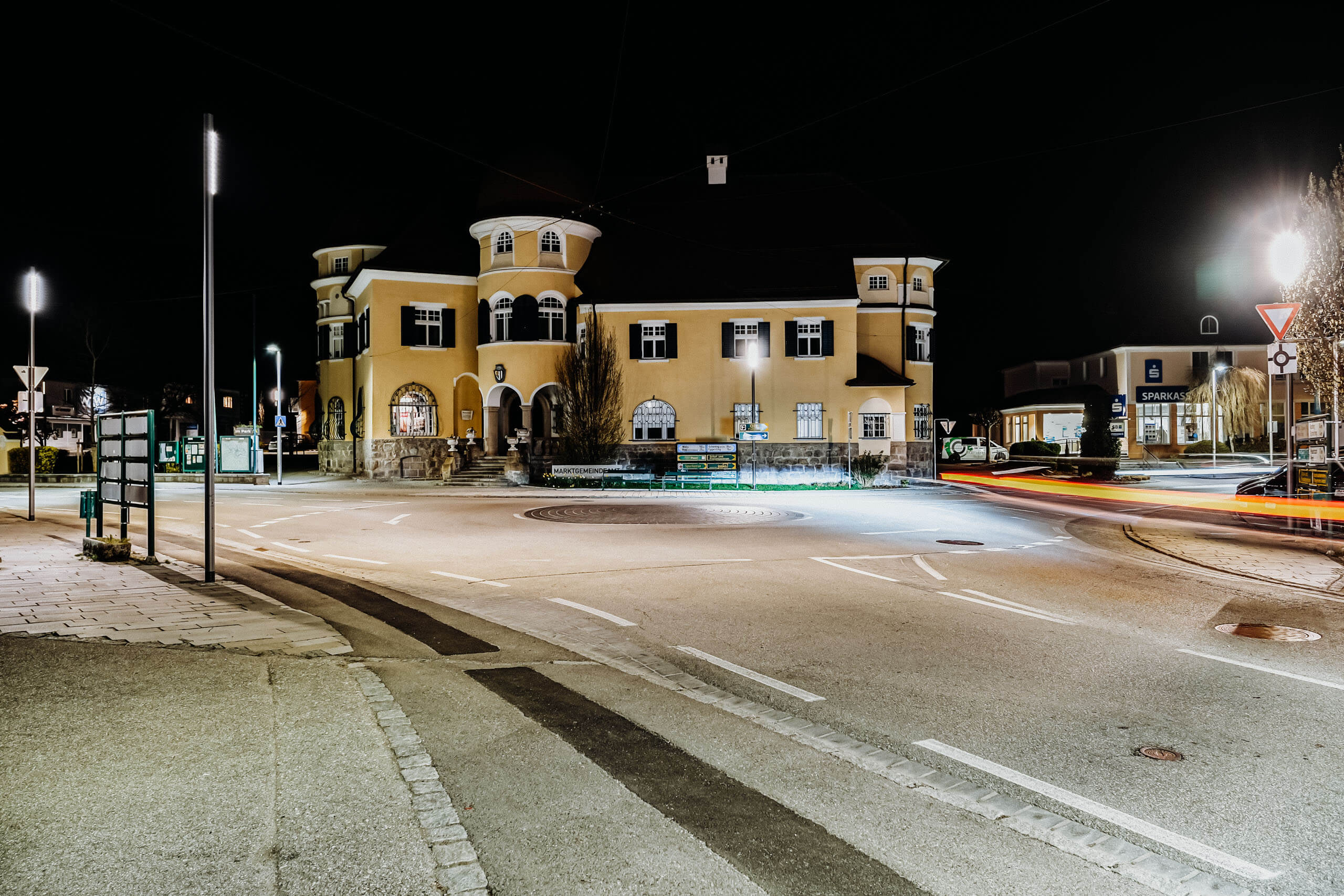 Straßenbeleuchtung beleuchtet Kreisverkehr und gelbes Gebäude bei Nacht