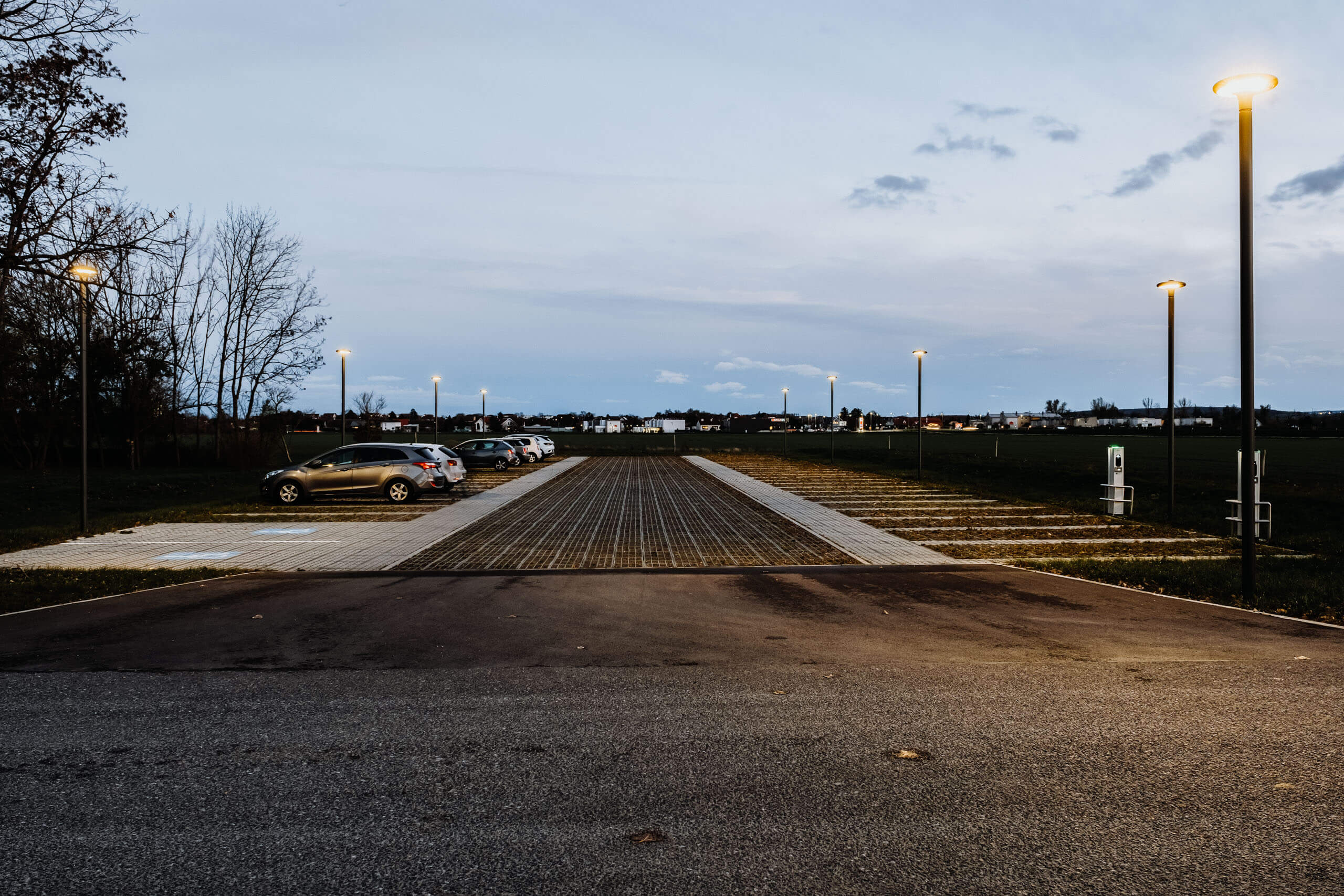 Gewerbepark mit Parkplätzen und Laternen im Abendlicht