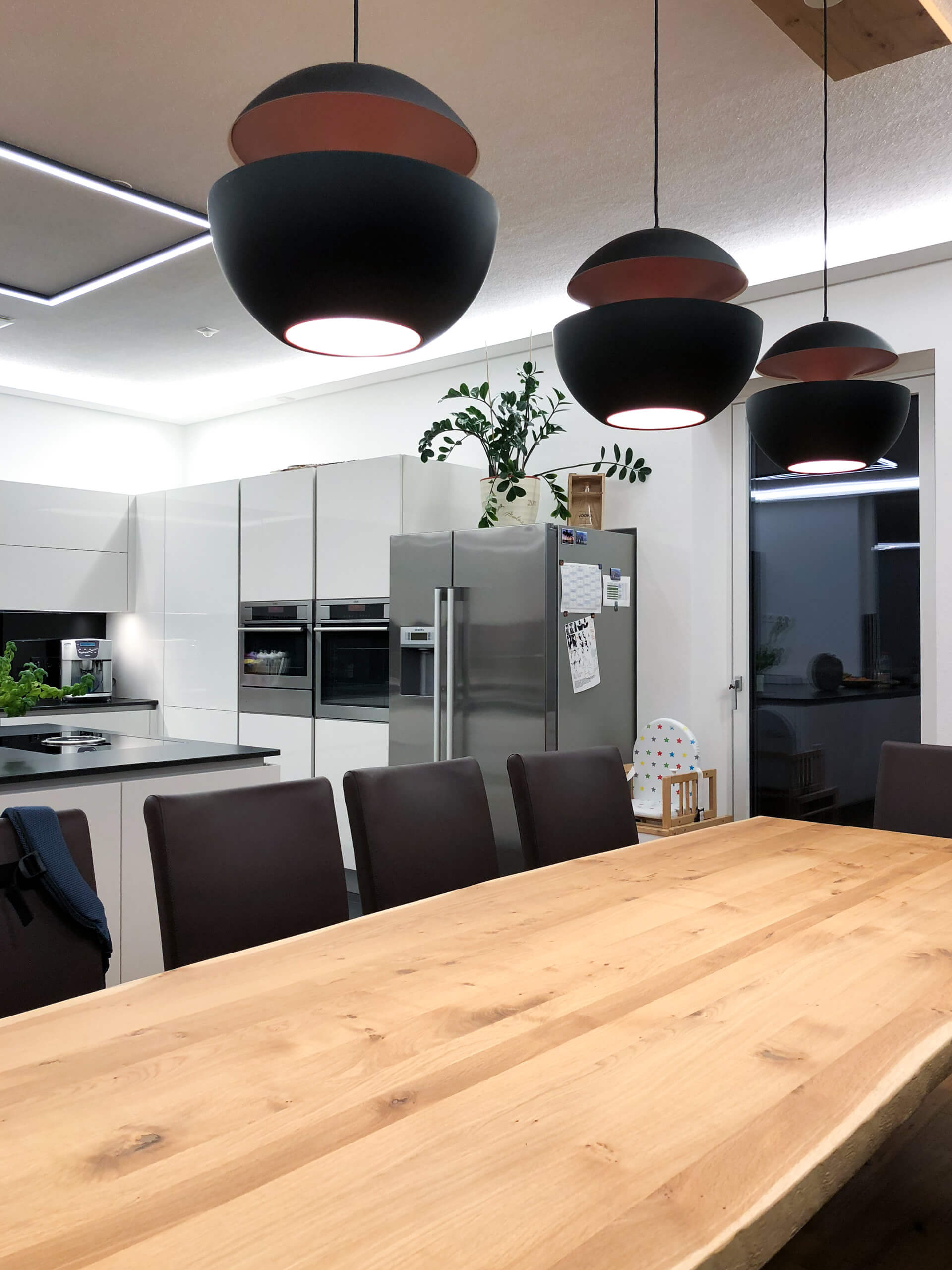 Moderne Essküche mit Esstisch, Stühlen und Hängeleuchten von Illumina.