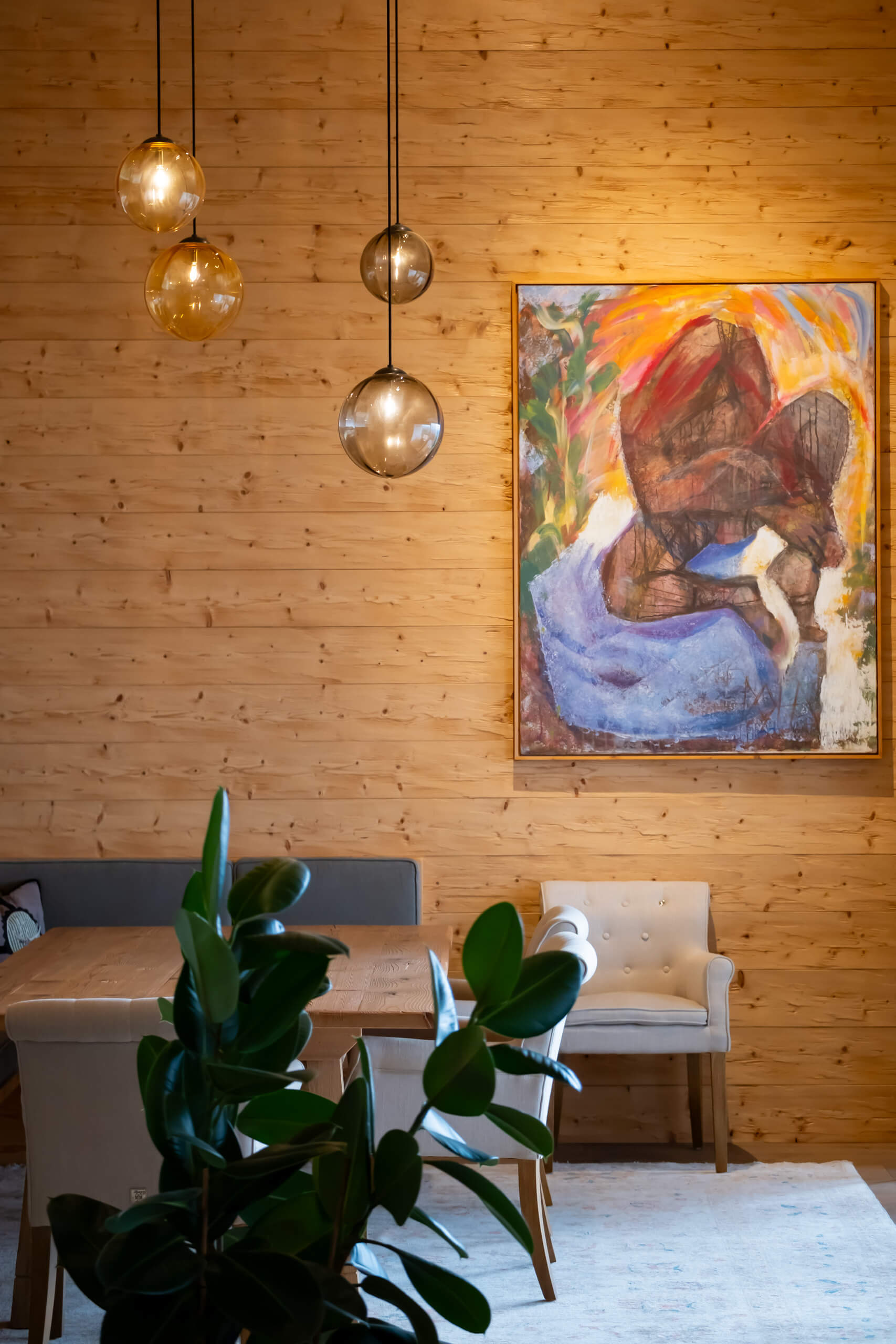 Gemütlicher Essbereich mit Holzwand und Kunstwerk – Lichtplanung von Illumina.