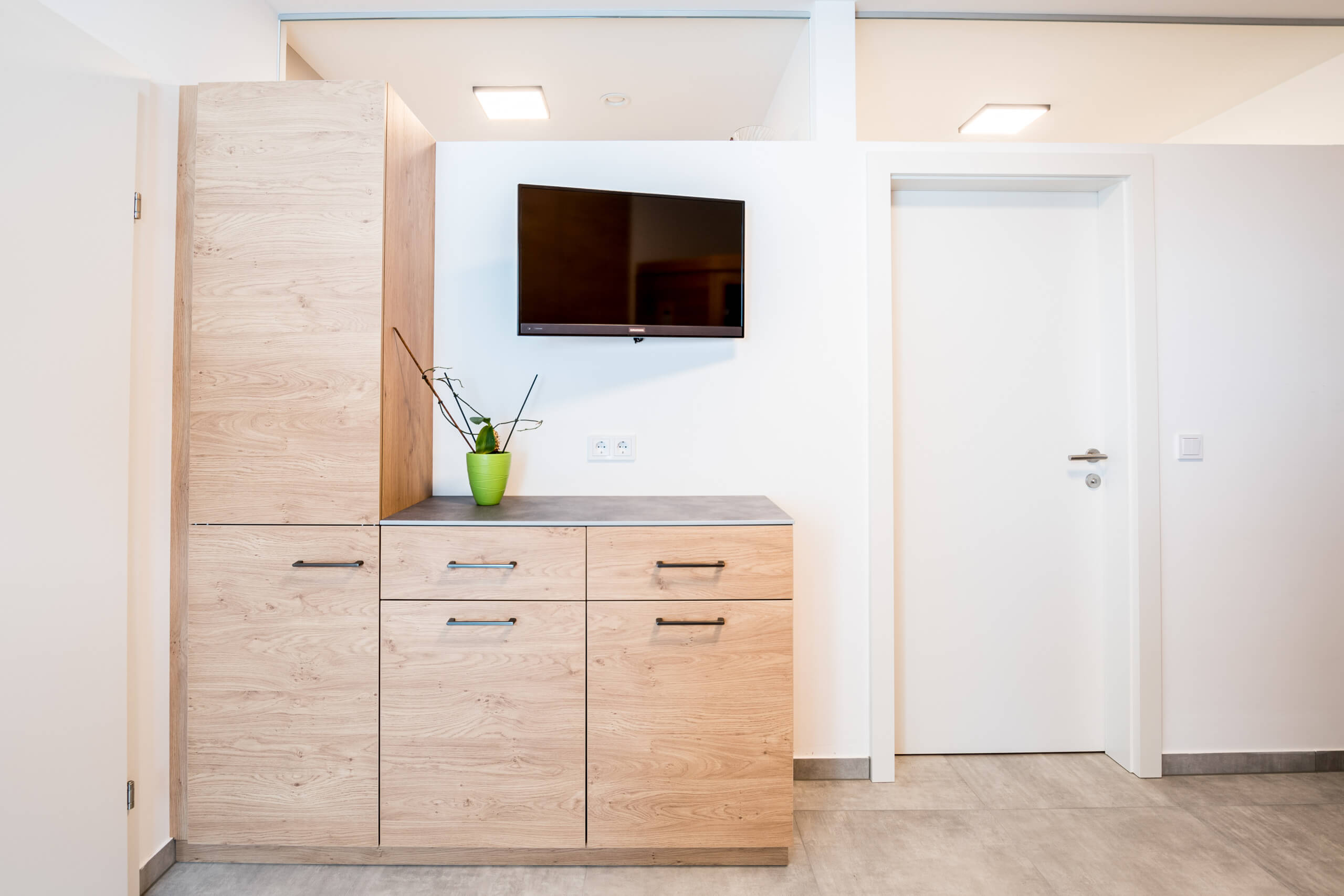Holzmöbel mit weißen Türen und einem Fernseher in einem modernen Raum