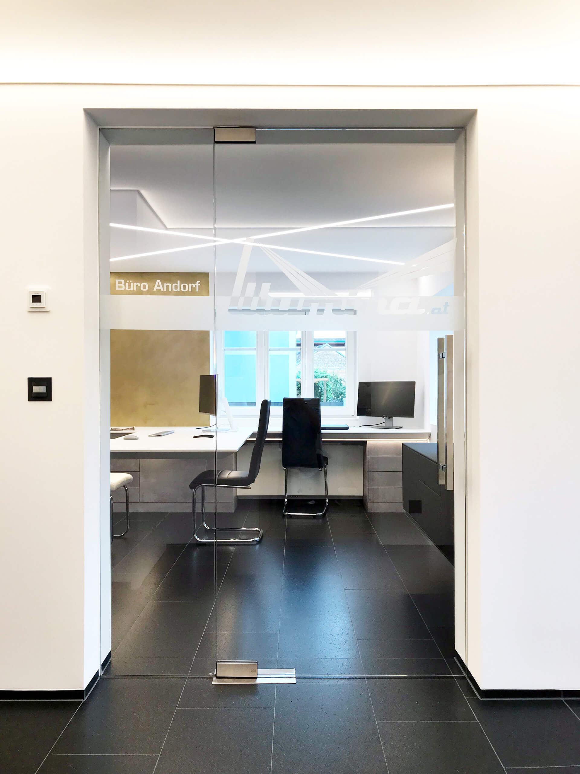 Büro Andorf mit moderner Glasfront und Schreibtisch – Lichtplanung von Illumina.