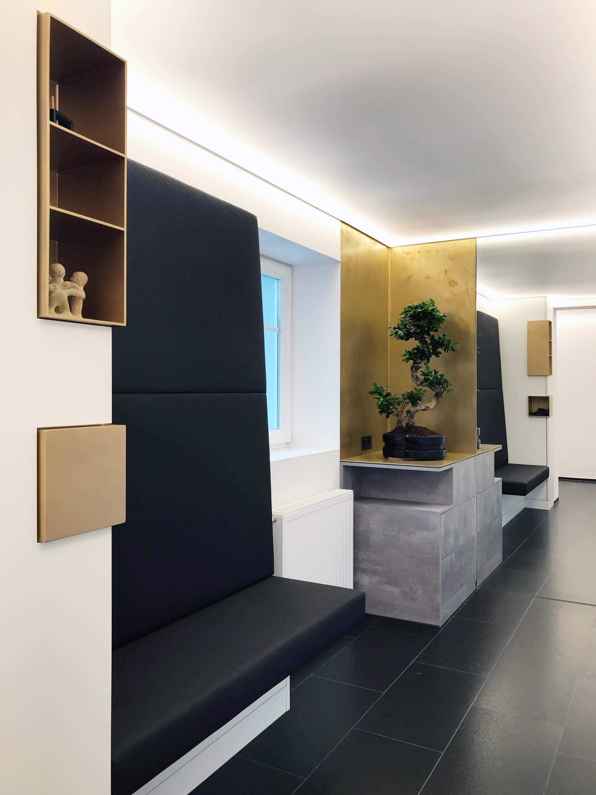 Moderne Wartezone mit integrierten Sitzbänken, Akzentbeleuchtung und Bonsai-Baum
