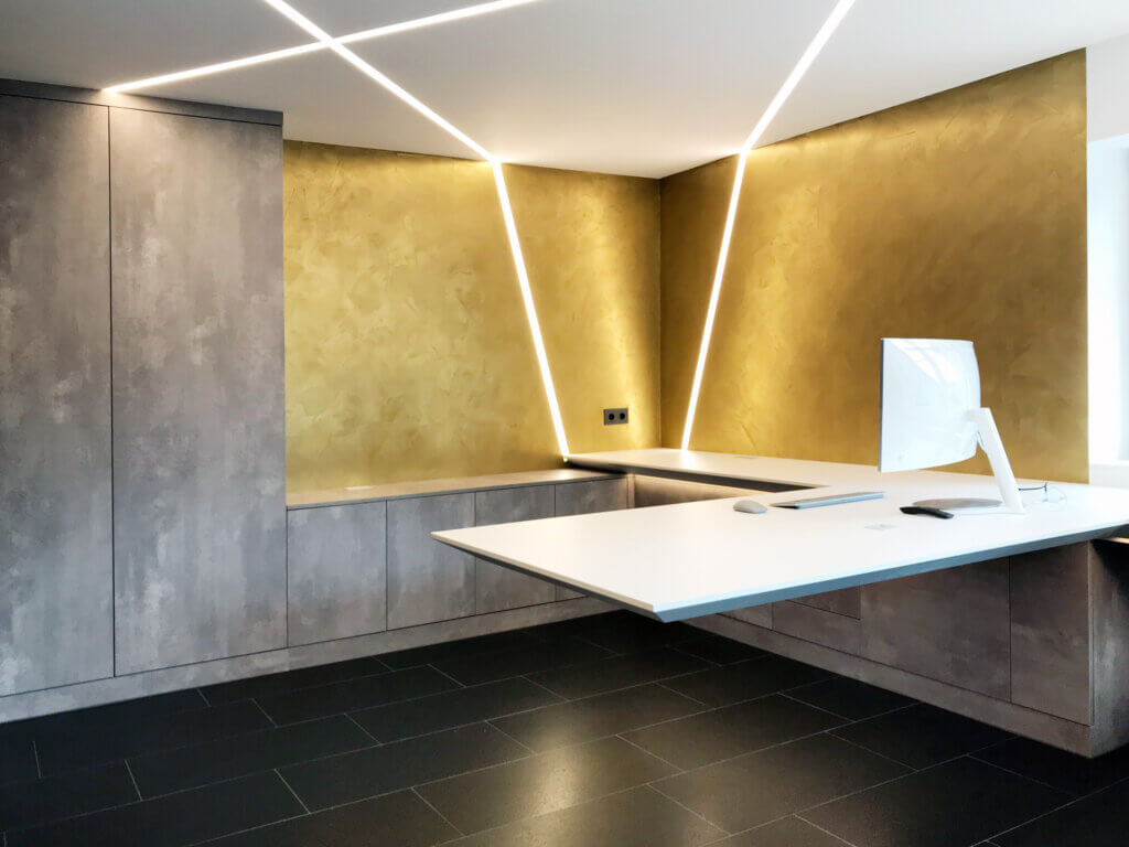 Modernes Büro mit goldener Wand, schwebendem Schreibtisch und indirekter Beleuchtung