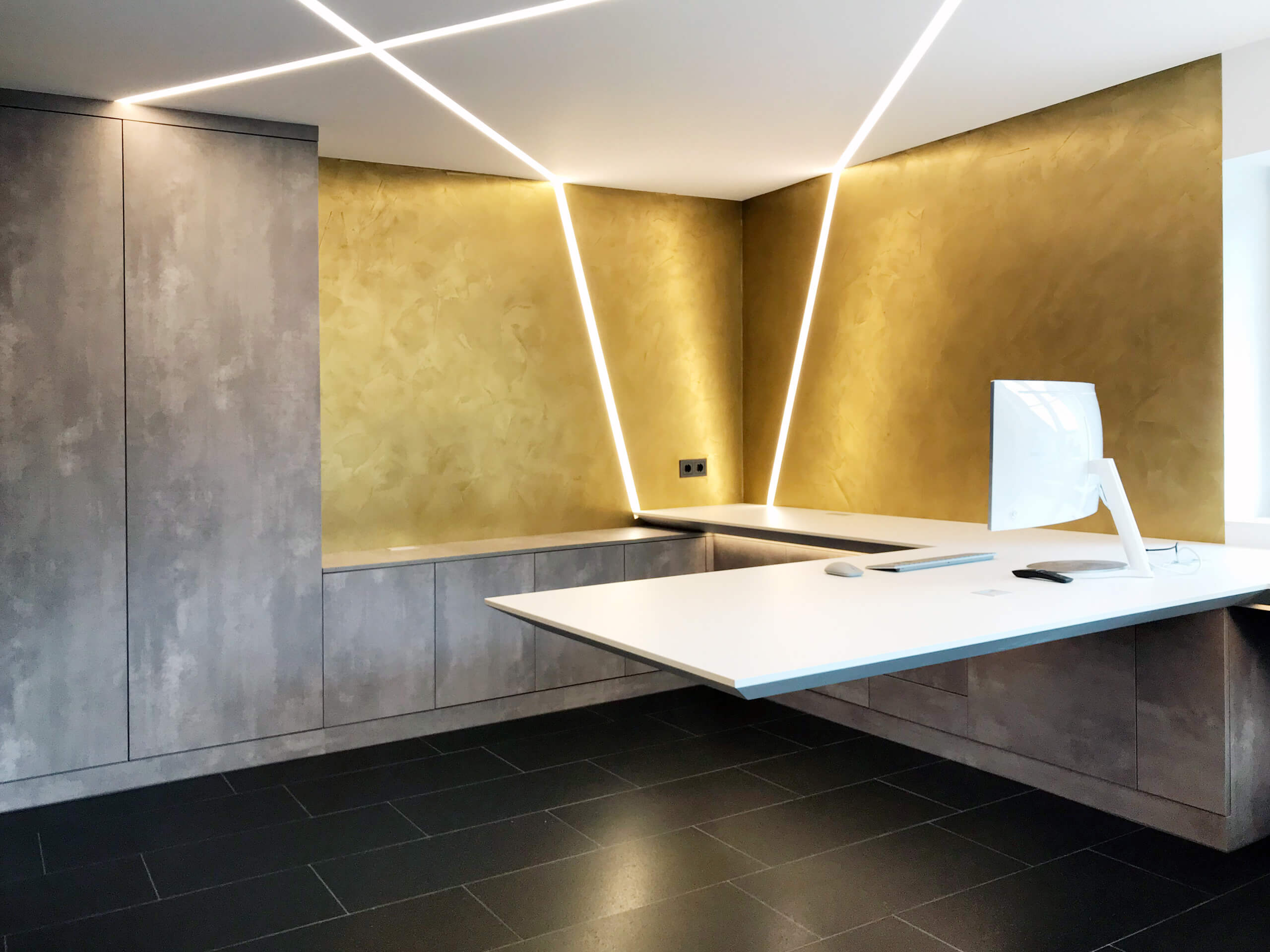 Modernes Büro mit goldener Wand, schwebendem Schreibtisch und indirekter Beleuchtung