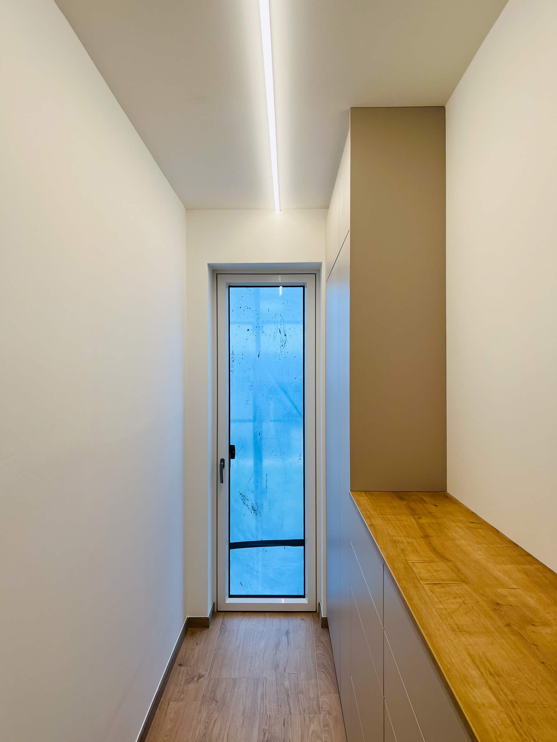 Flur mit Holzboden, weißer Wand und integrierter Beleuchtung