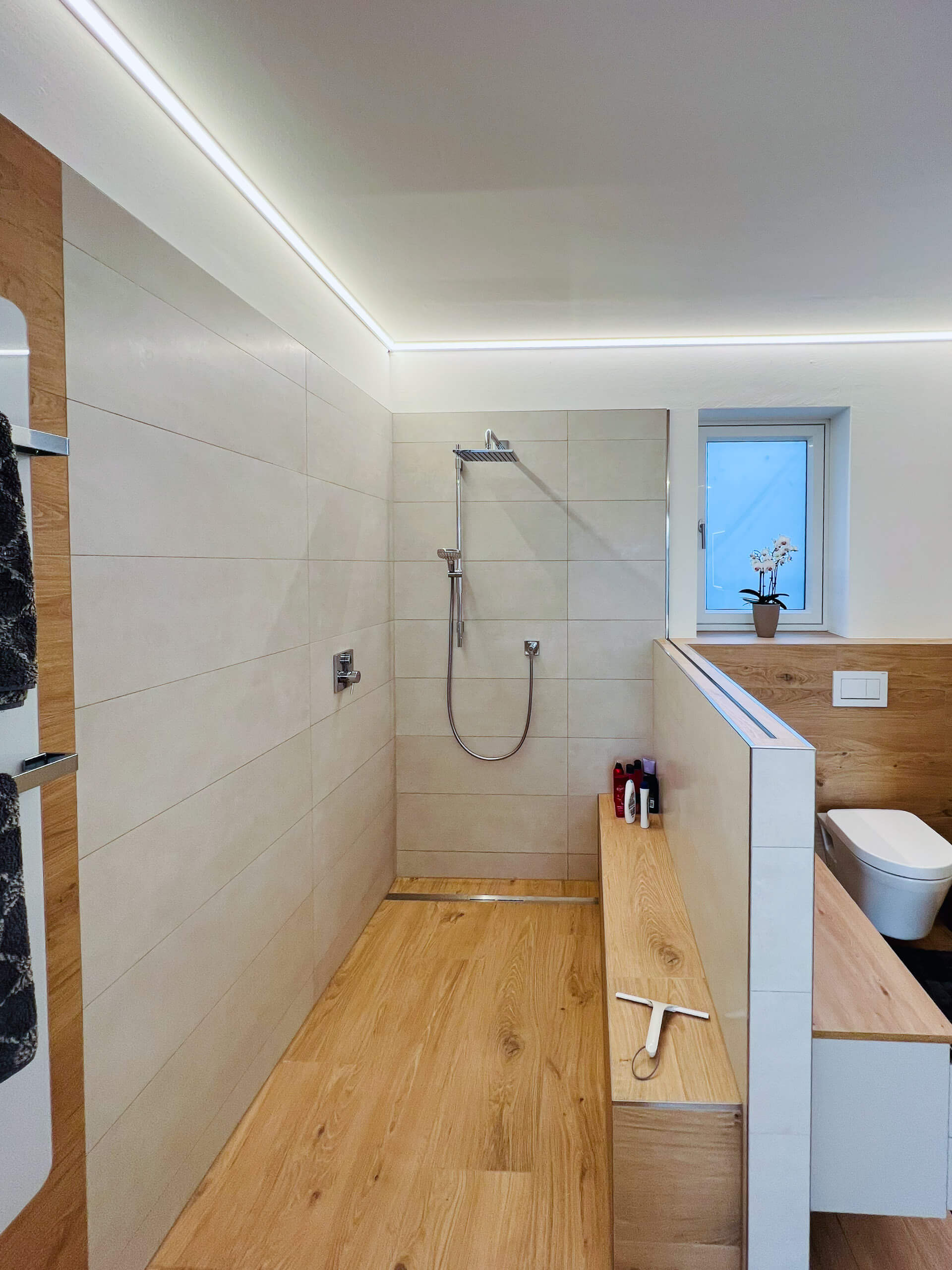Beleuchtete Dusche mit Holzboden und Wandverkleidung