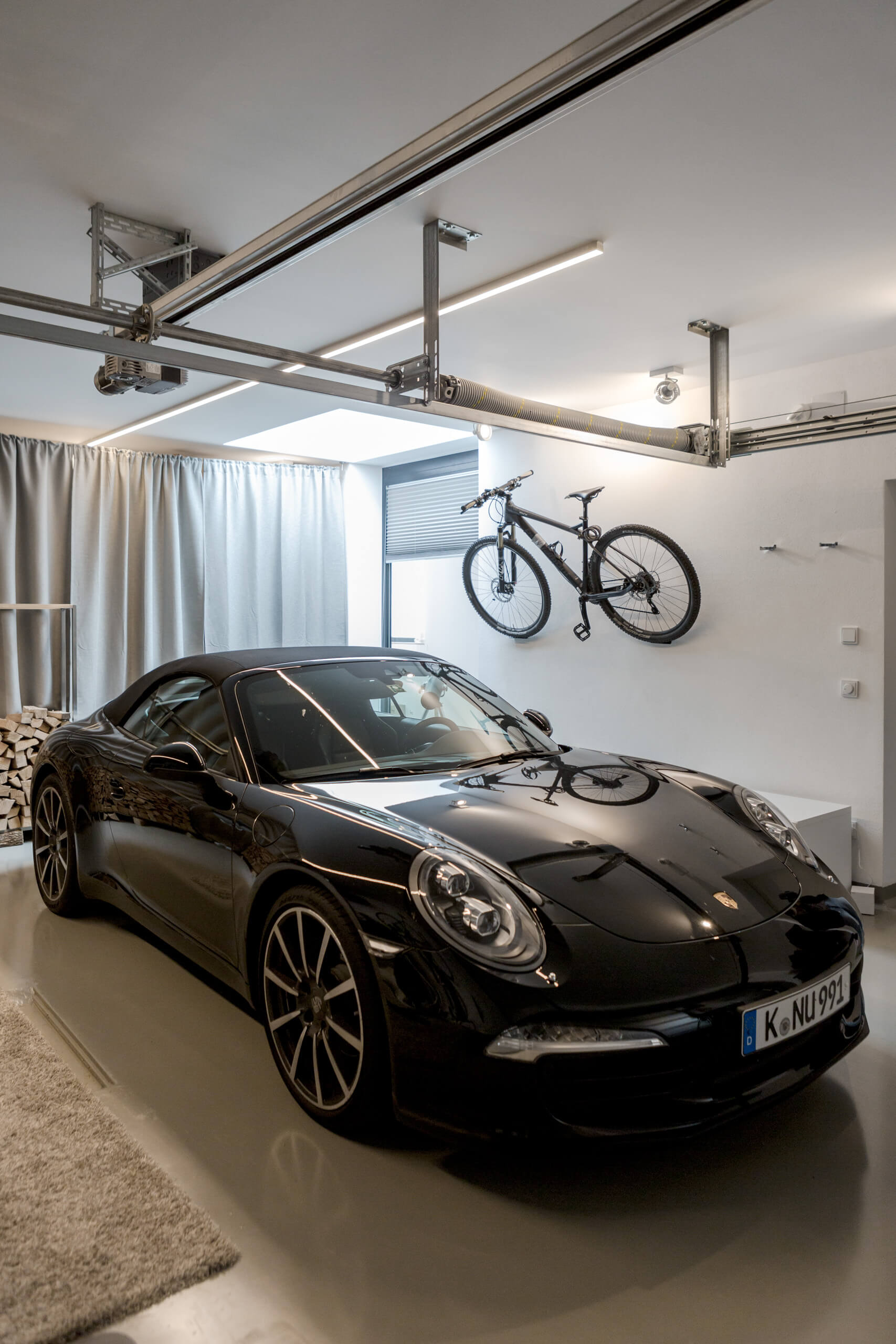 Schwarzer Porsche im modernen Garagenraum mit Fahrrad und indirekter Beleuchtung